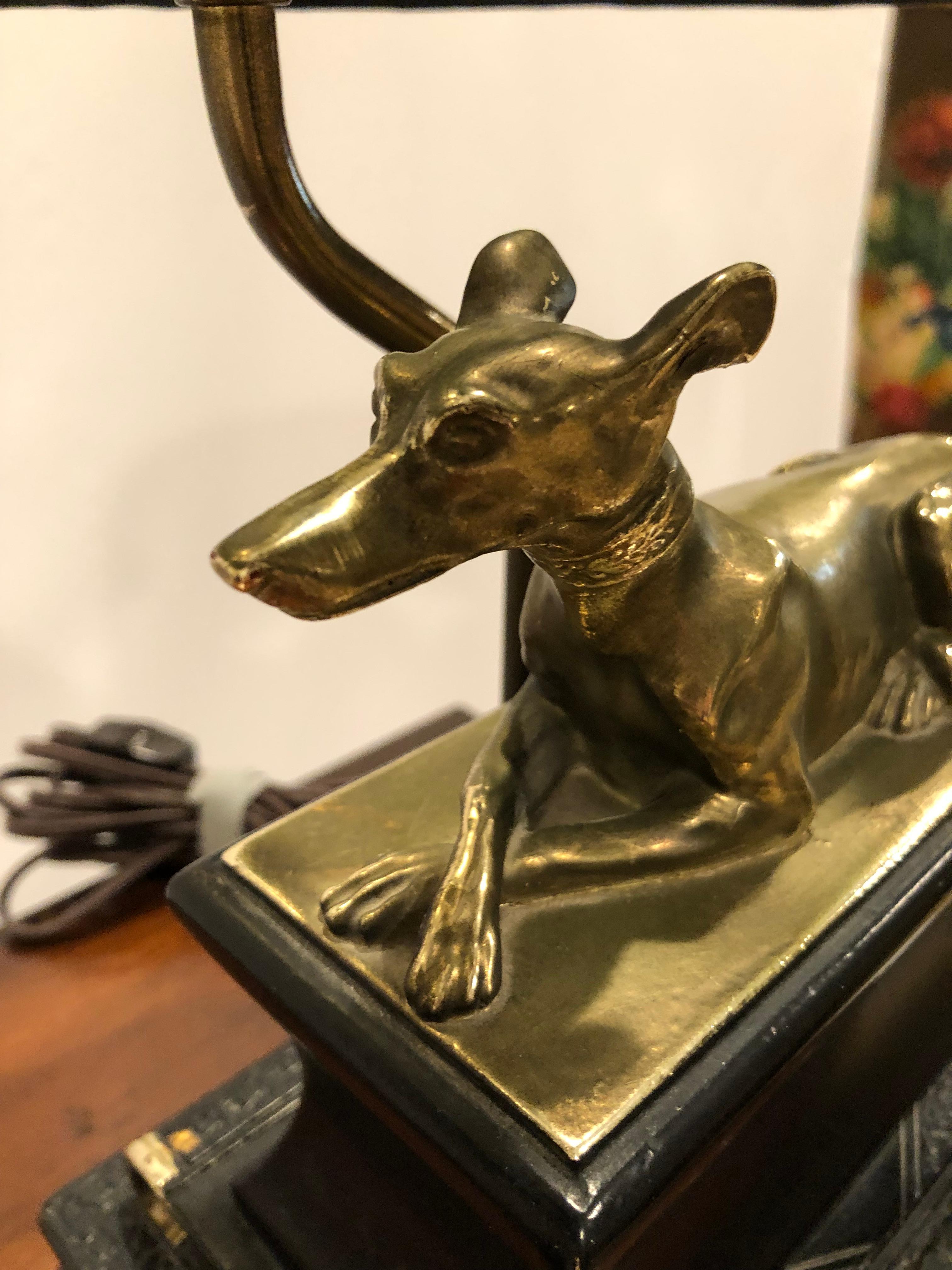 Wonderful pair of black and gold table lamps having brass reclining greyhound dogs on faux leather book stands. Shades are a handsome oval shape ,12