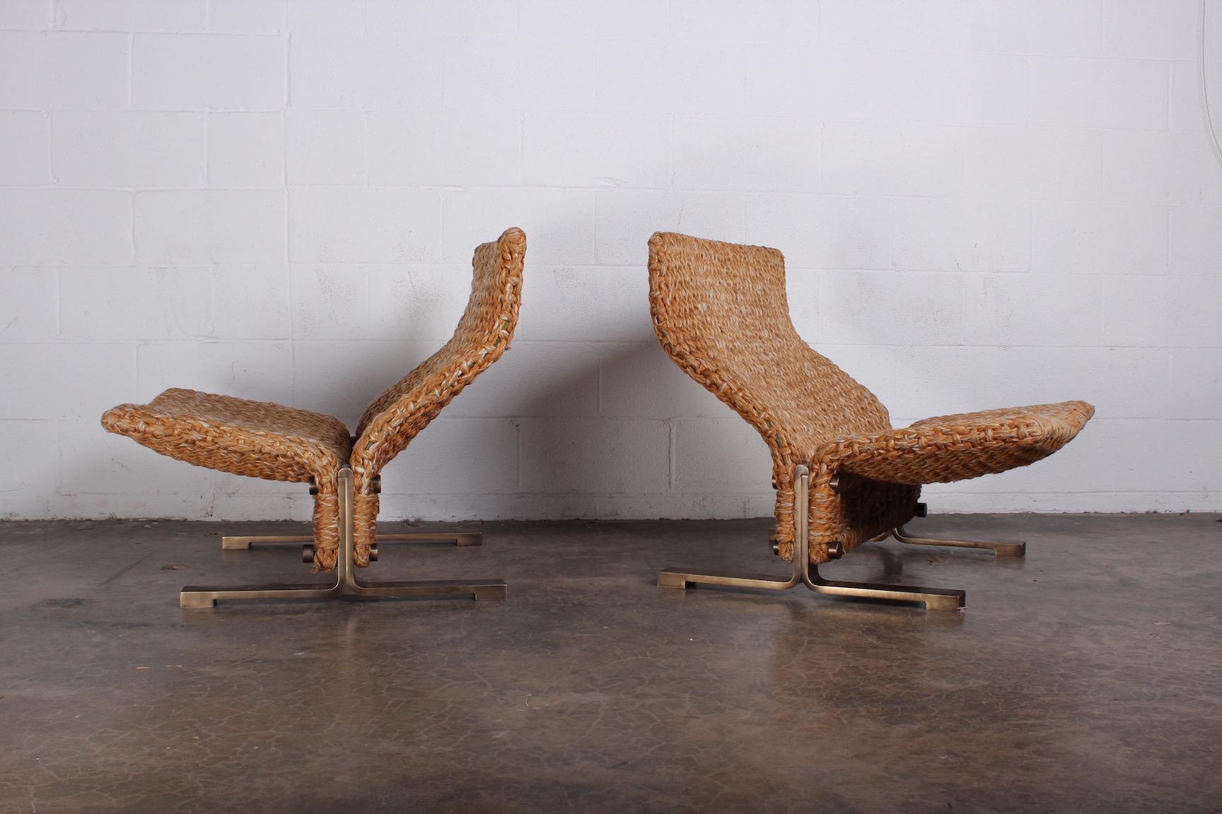 A pair of lounge chairs with solid patinated brass bases and woven rope seats. Designed by Marzio Cecchi.
