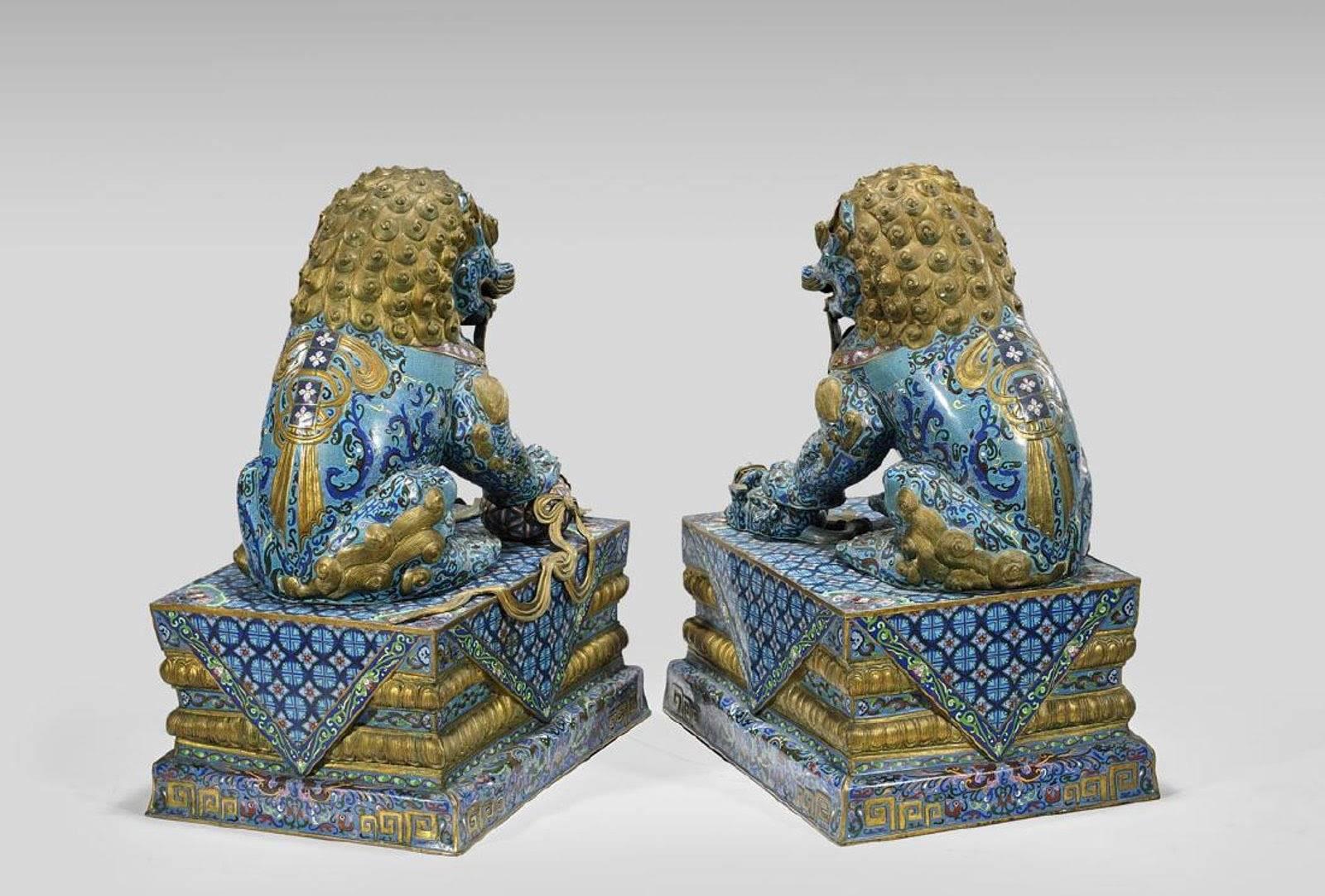 Pair of massive Chinese cloisonné enamel guardian lions; each parcel-gilt and finely detailed with scrolling lotus motifs on turquoise grounds, and pending a bell at the neck; the female with a cub under her paw, the male with a ball; each on an