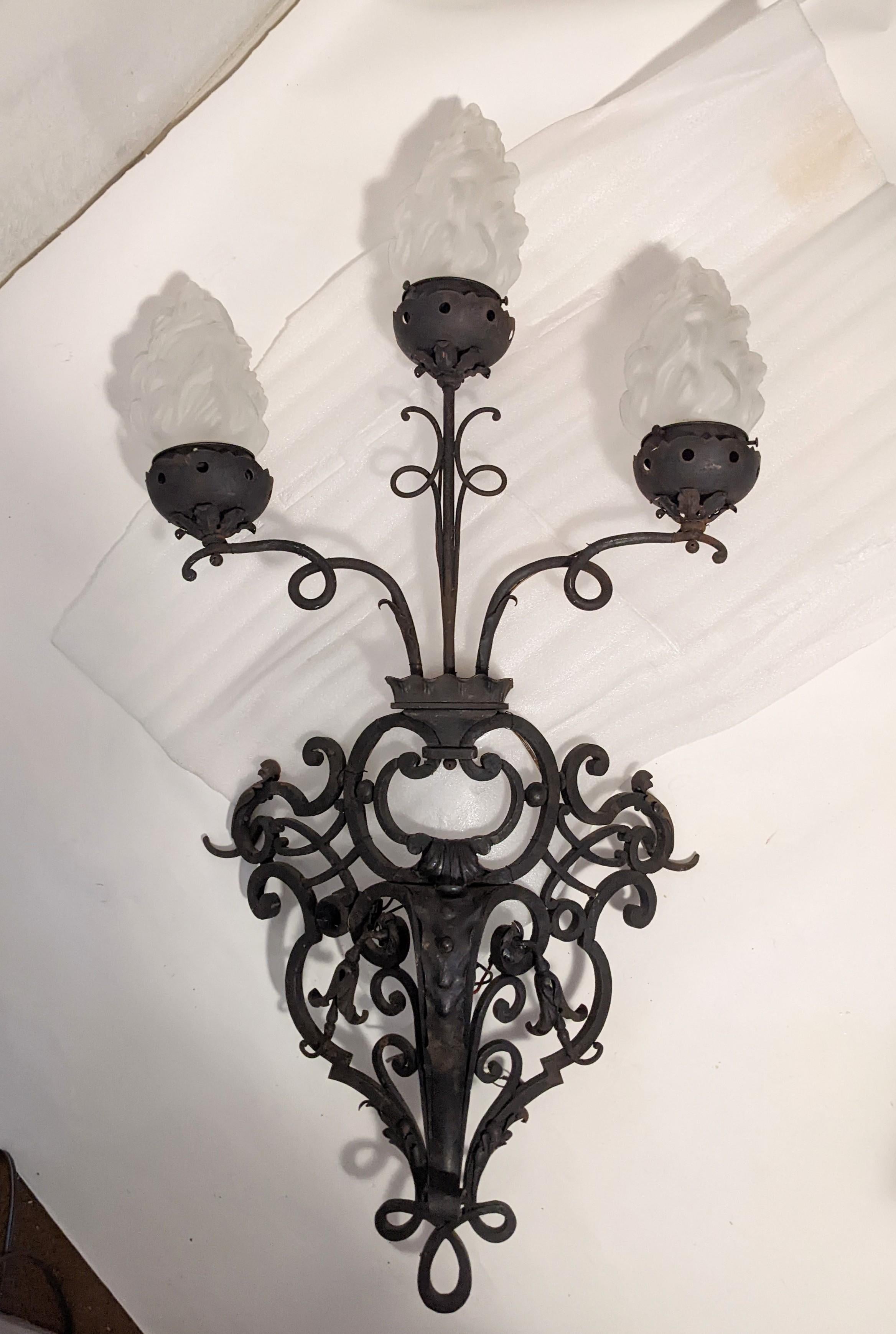 Massive French wrought iron sconces with frosted flame globes suitable for interior or exterior use from the 1930's. From an important, massive estate in Westchester NY, these monumental sconces have a scale perfect for a large outdoor area or a
