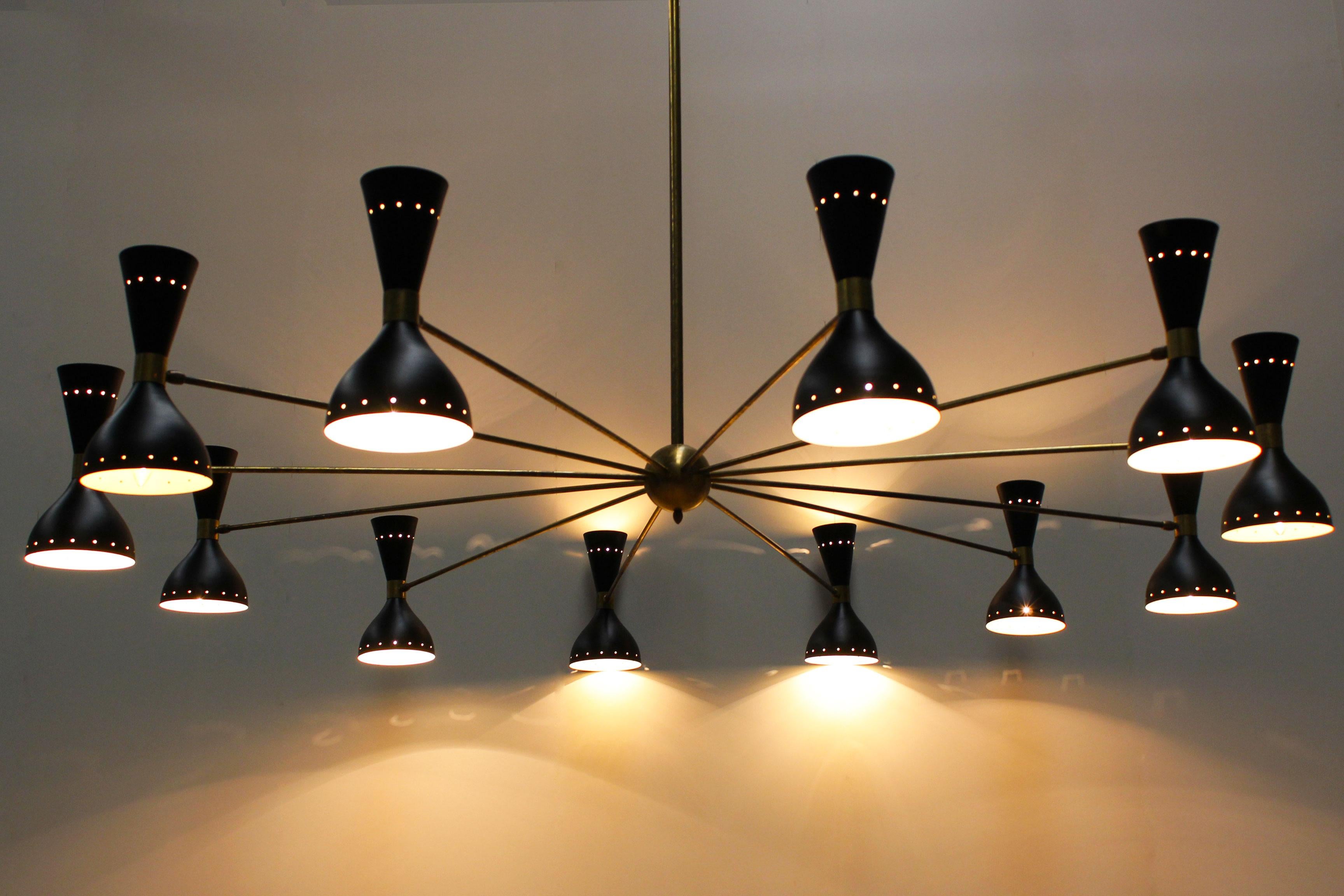 Massiccio lampadario italiano della metà degli anni '50 in stile Stilnovo con un diametro di 190 cm. Il lampadario ha 24 prese, 12 rivolte verso l'alto e 12 verso il basso. Il lampadario ha una struttura in ottone e paralumi in metallo nero. La sua