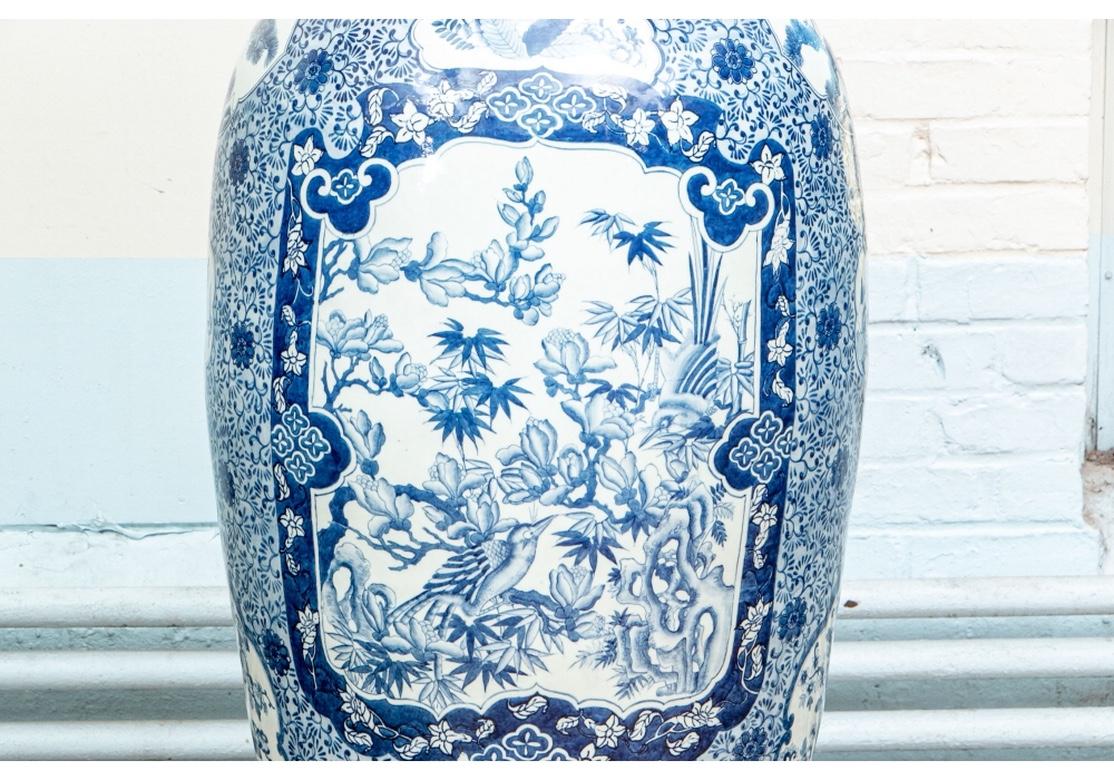 Blue and white with large and small panels decorated with birds, flowering trees, and vases with flowers. Overall blue vine and rosette patterned background and decorative bands on the necks and bases. Elegant ruffled rims. With carved ebonized wood