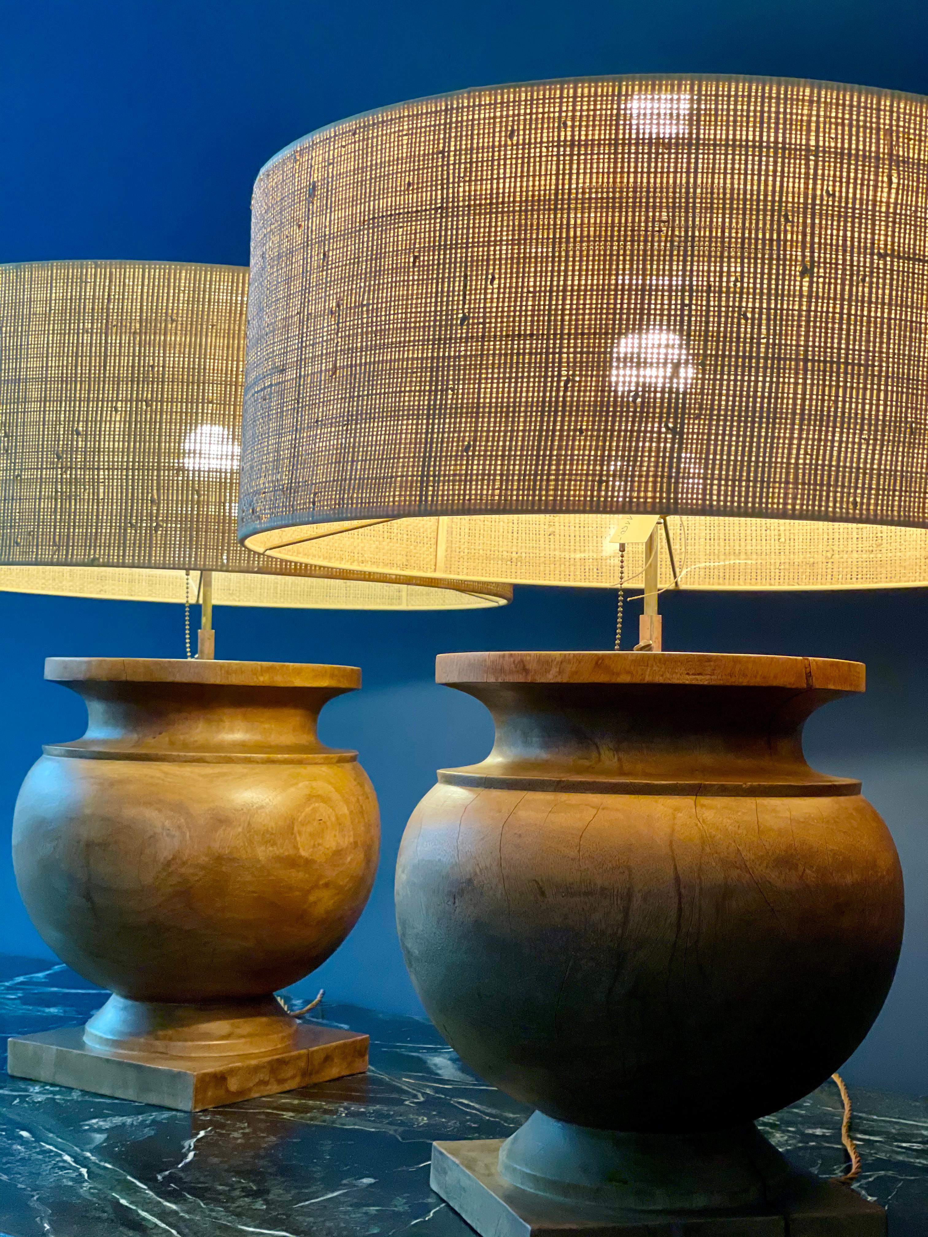 Large wooden table lamps from France. Paired with handmade raffia lamp shades these lamps also have a beautiful wood patina. There are shrinkage cracks which is normal considering their age.