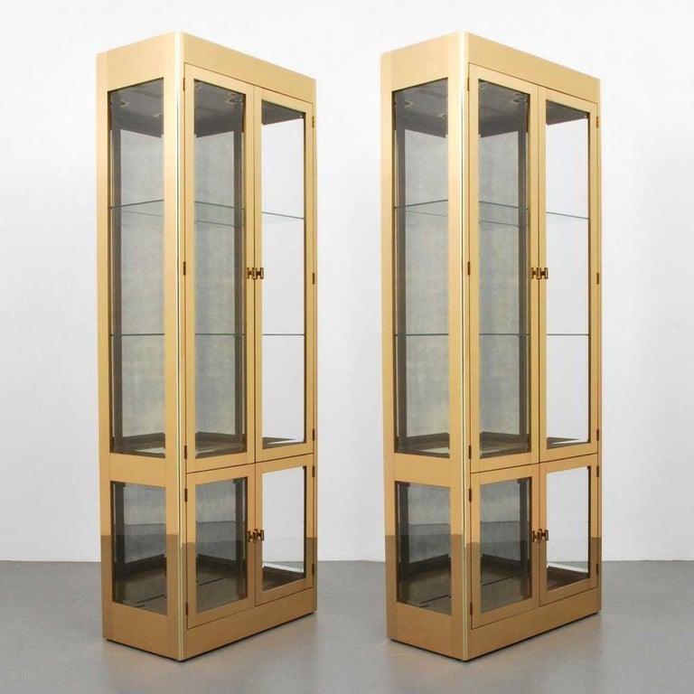 Offered is a pair of Mastercraft vitrines with highly polished lacquered brass along with two main compartments: two adjustable glass shelves in the top section and one in the lower section, interior lighting. Magnetic door closures with rectangular