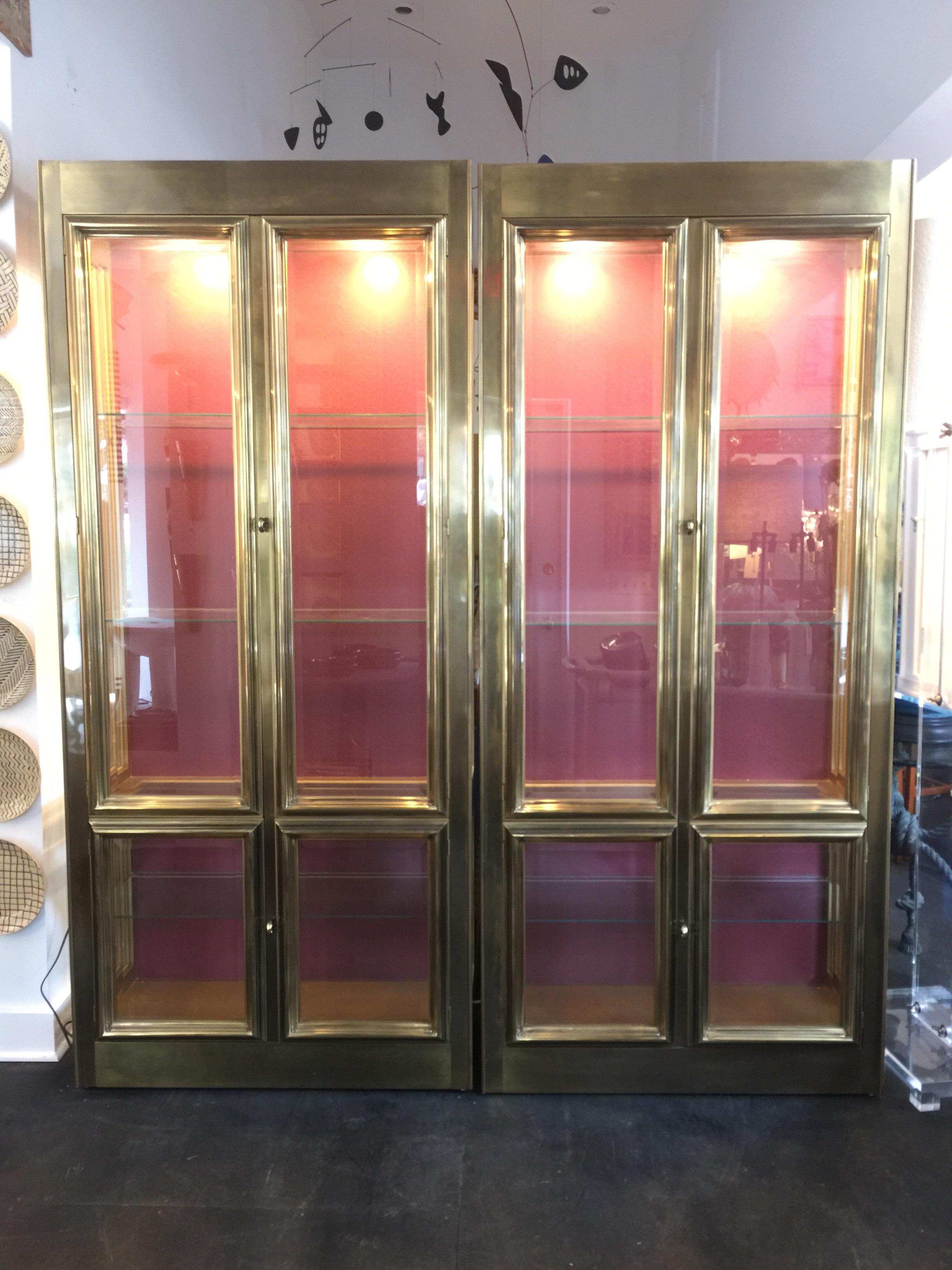 Pair of brass mastercraft cabinets / vitrines with bevelled glass doors and four interior adjustable shelves. Wonderful brass molding throughout - two downlights in each cabinet.

American, circa 1970s. Having four doors/ four glass shelves and