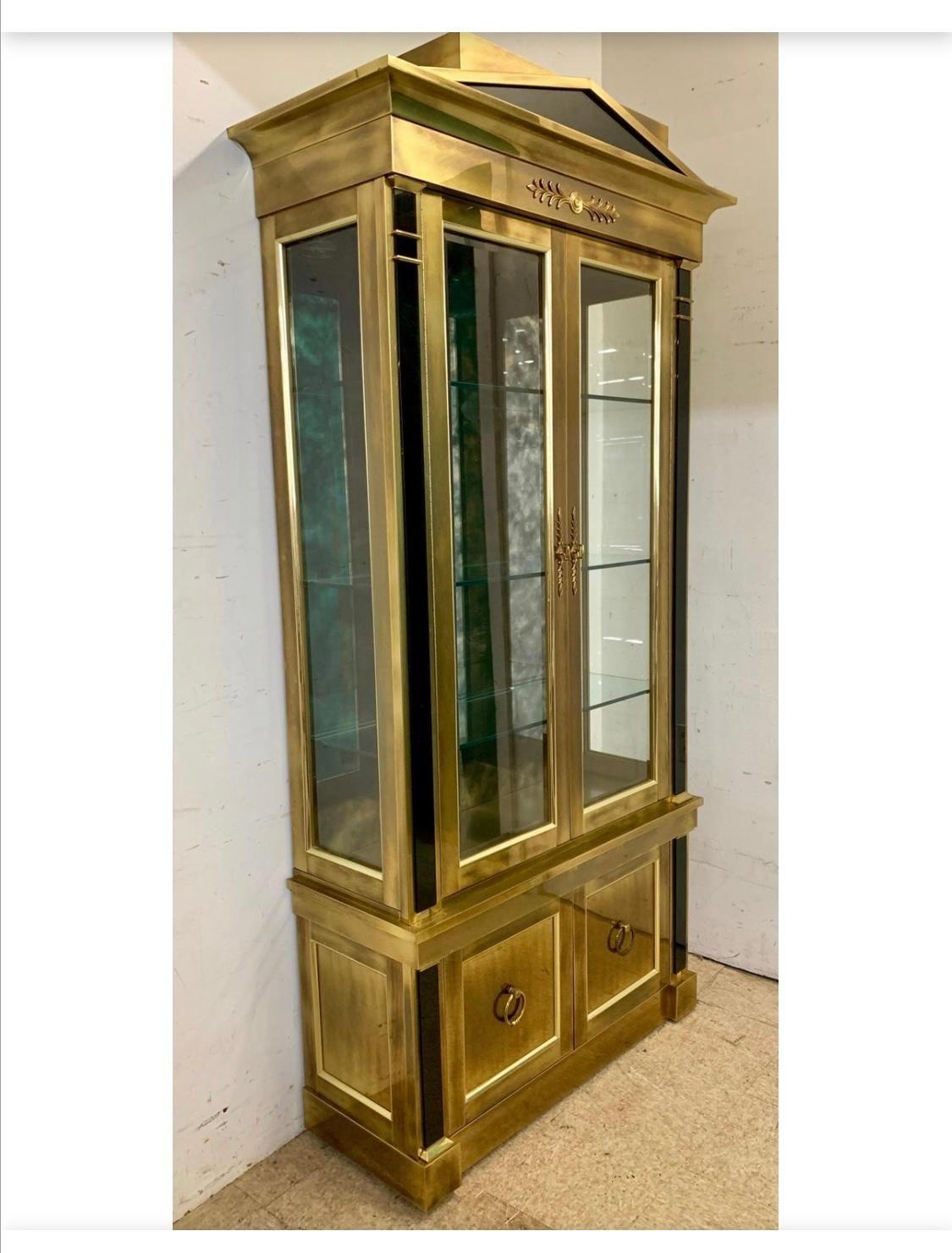Pair of elegant brass vitrines/displays by Mastercraft with two doors with beveled glass and two small ones below. Beautiful antiqued mirror inside each vitrine and two lights on top. Made in USA, c. 1970's.
