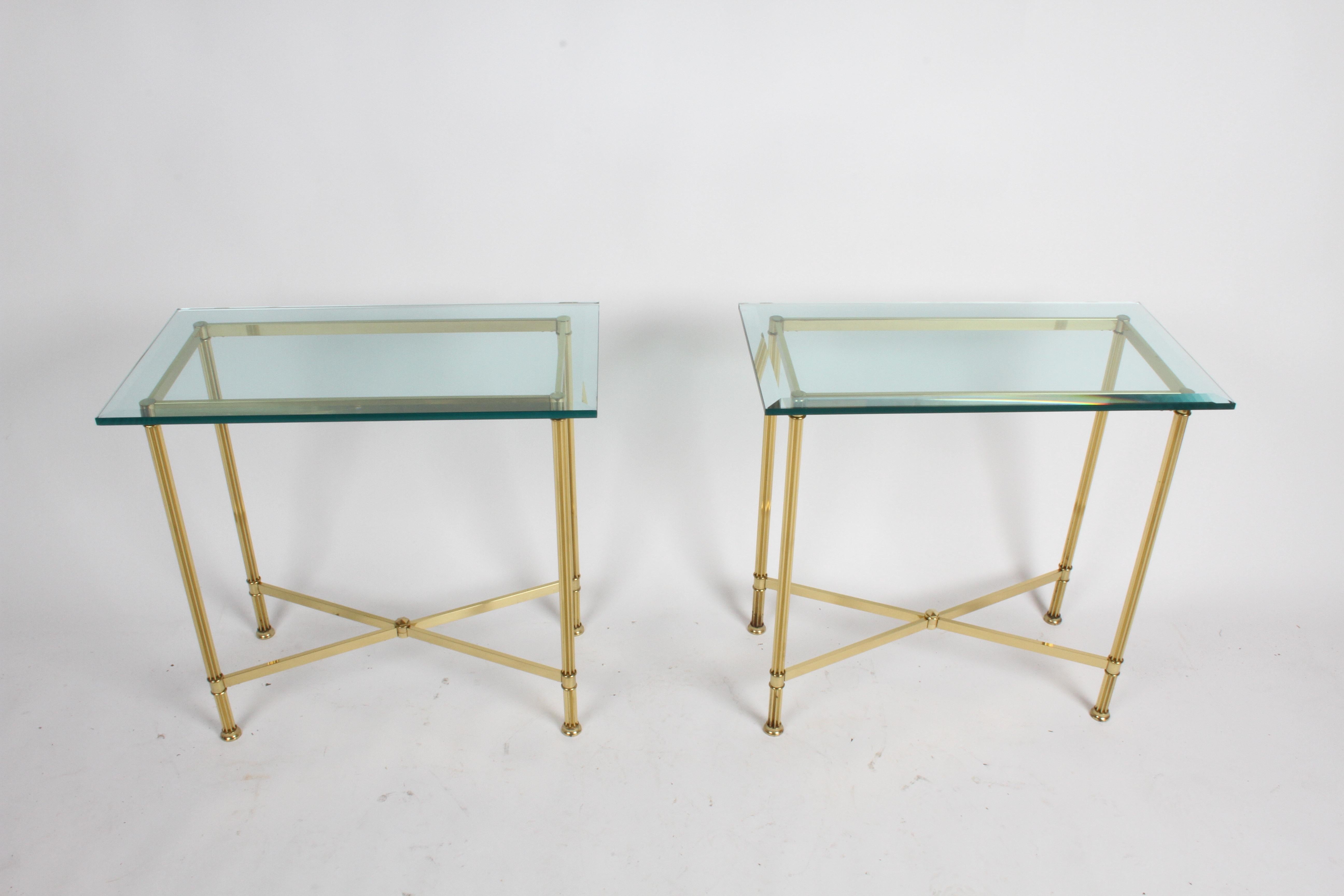 Pair of matching Mastercraft rectangle console tables with beveled glass tops on elegant fluted brass column legs with X-stretcher bracing. Brass is in very nice condition, with factory applied patina. Few minor chips to corners of glass, glass is