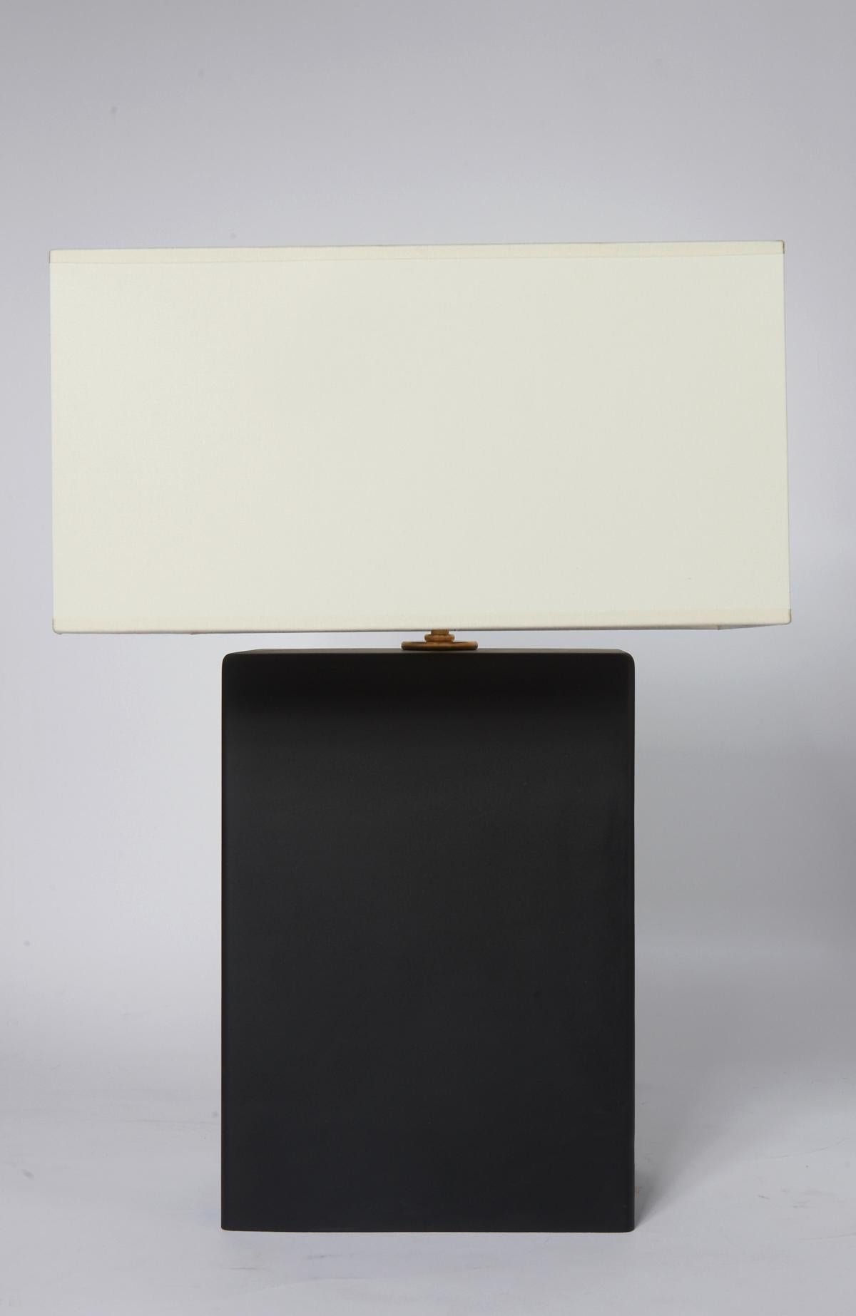 Pair of rectangle shaped table lamps made of glass in mat black with brass hardware.