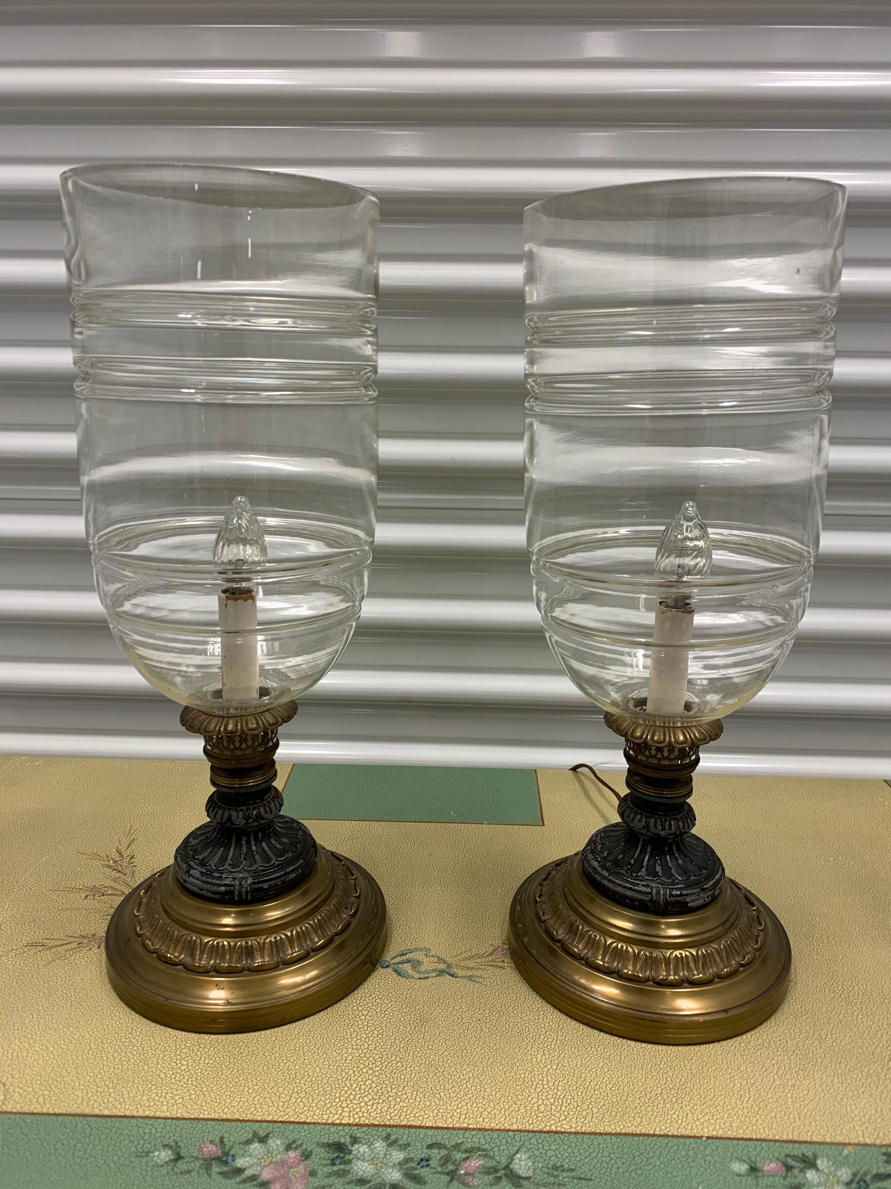 Elegant pair of matching 19 inch tall hurricane lamps that are seven inches in diameter. Brass base under a painted metal black base and then large crystal hurricane pieces. Fully electrified for USA and in working order.