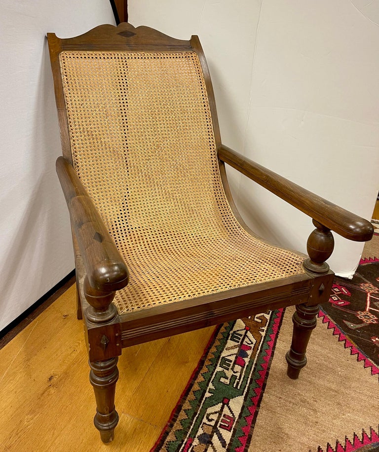 British Colonial plantation chairs feature a carved frame with cane seat and back. Hand made with swing out extension arms that transform into leg rests and can be tucked back under the arms.