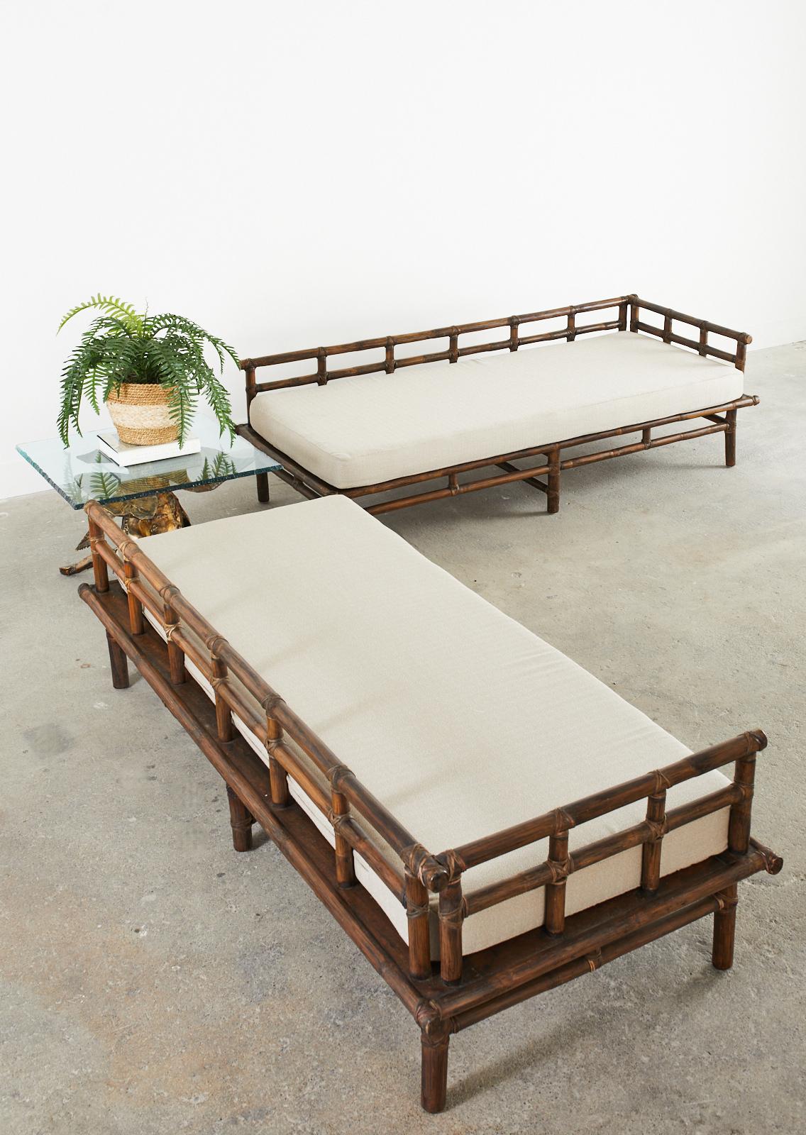 Distinctive pair of matching bamboo rattan daybeds or sofas hand-crafted in the California organic modern style by McGuire. The pair feature a sturdy rattan and oak frame lashed together with leather rawhide laces and end caps. The back supports