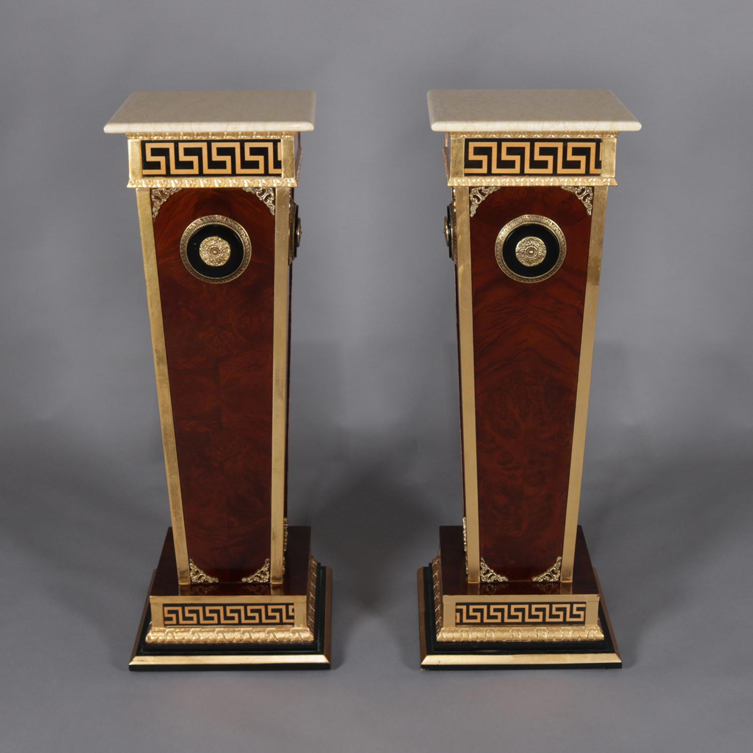 A pair of matching neoclassical sculpture display pedestals feature flame mahogany with gilt Greek Key banding, cast ormolu mounts including central medallions, and supporting cast faux marble resin display, 20th century

Measures: 39