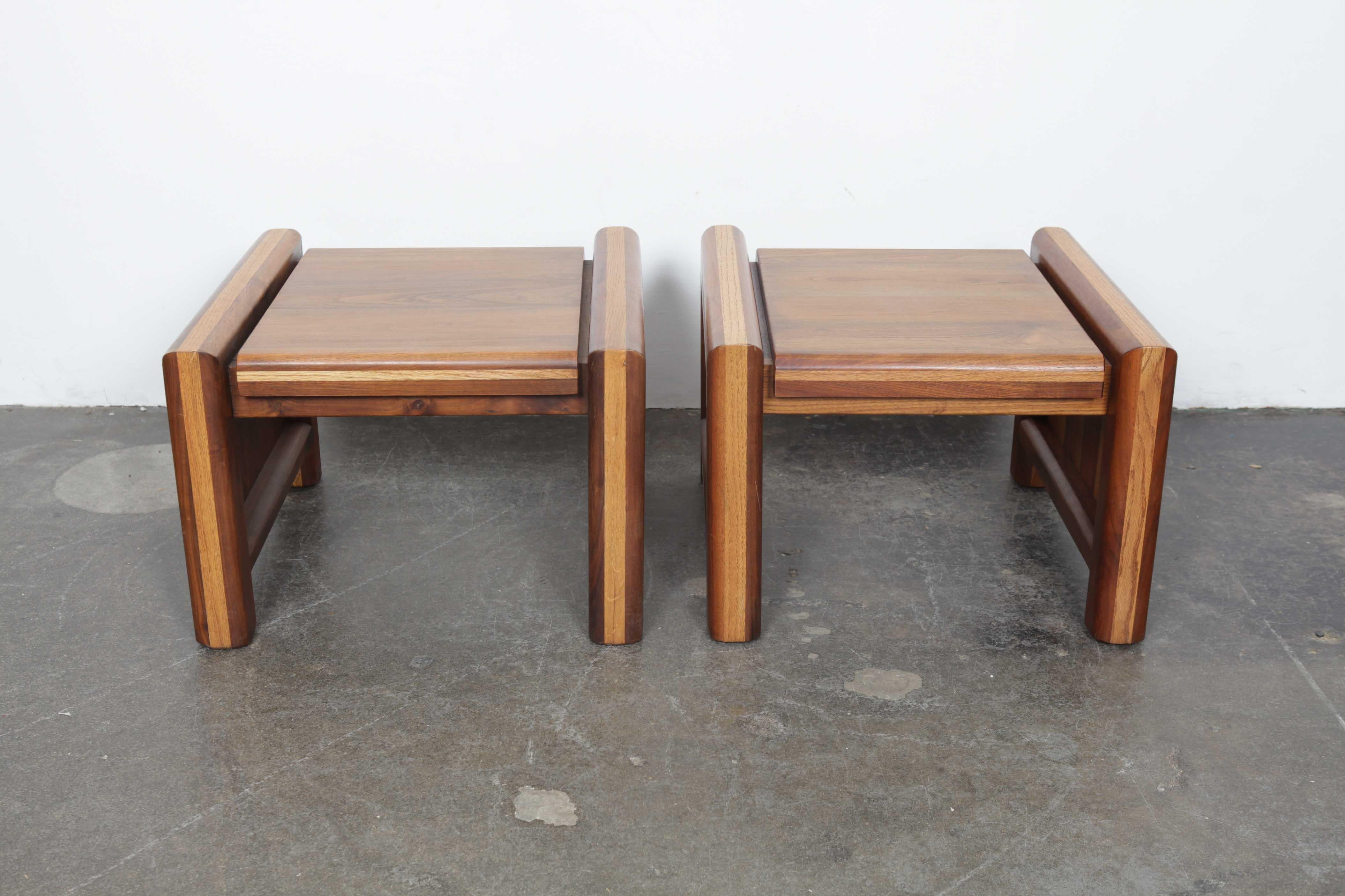 Pair of American made 1970s multi-tone walnut end tables with rounded legs and solid sides. Designer and maker are unknown.