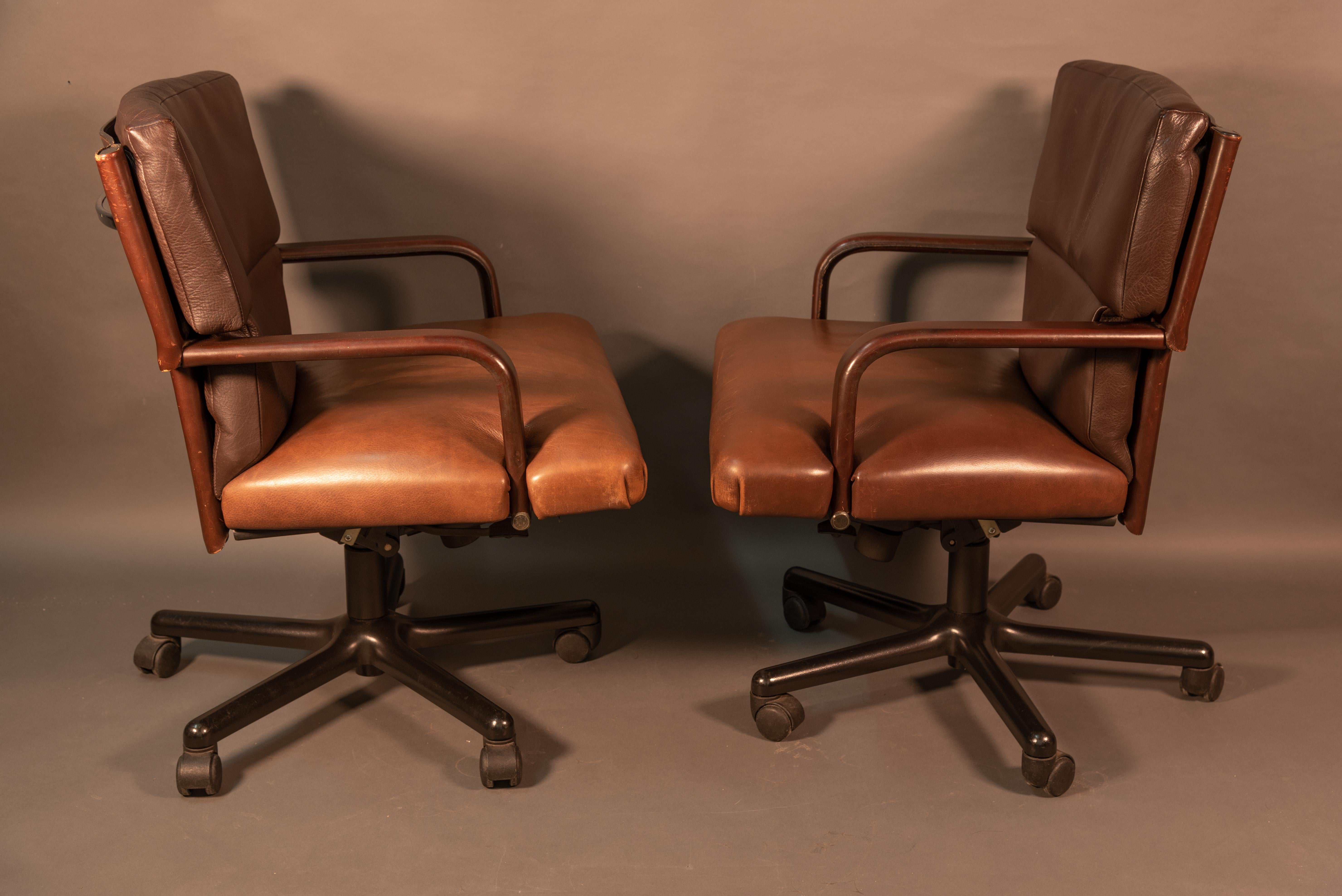 Pair of Matteo Grassi armchairs. The armrests are covered in leather.
There's a mechanism under the seat with two levers to adjust the seat height. 
The five swivel wheels are completely black polyamide, suitable for soft floors. 
They have a