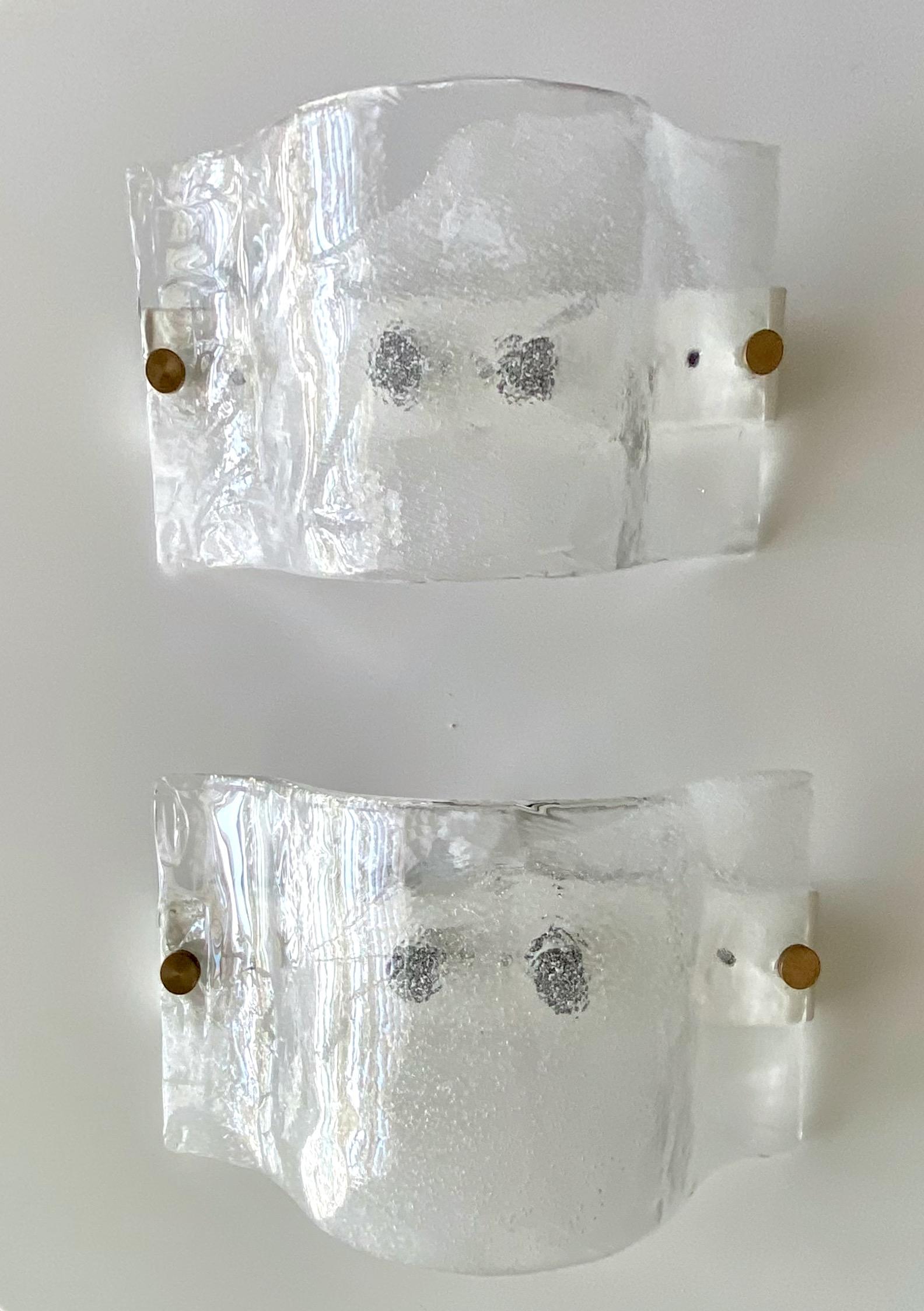 Pair of handblown Murano clear and textured glass sconces by Carlo Nason for Mazzega, white backplates with brass mounting screws. Rewired. Each takes two candelabra size bulb.