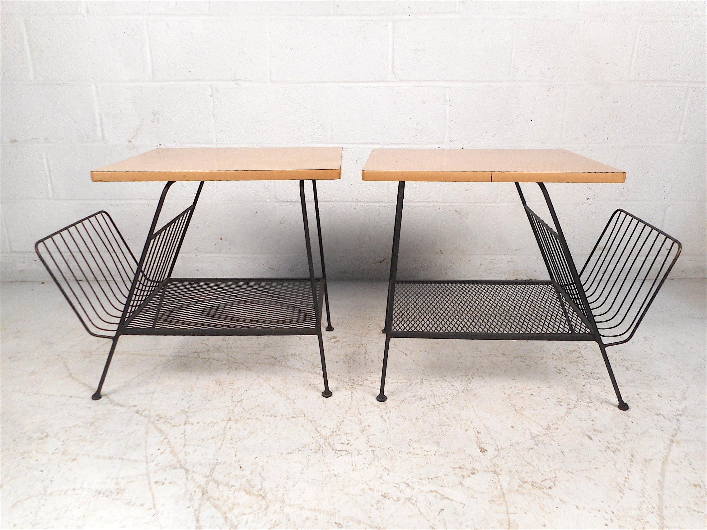 Interesting pair of side tables with magazine racks attached, in the style of Paul McCobb. These petite end tables have laminate table surfaces with a mock wood-grain pattern, the frame is constituted of iron with a black finish. Stylish pair sure
