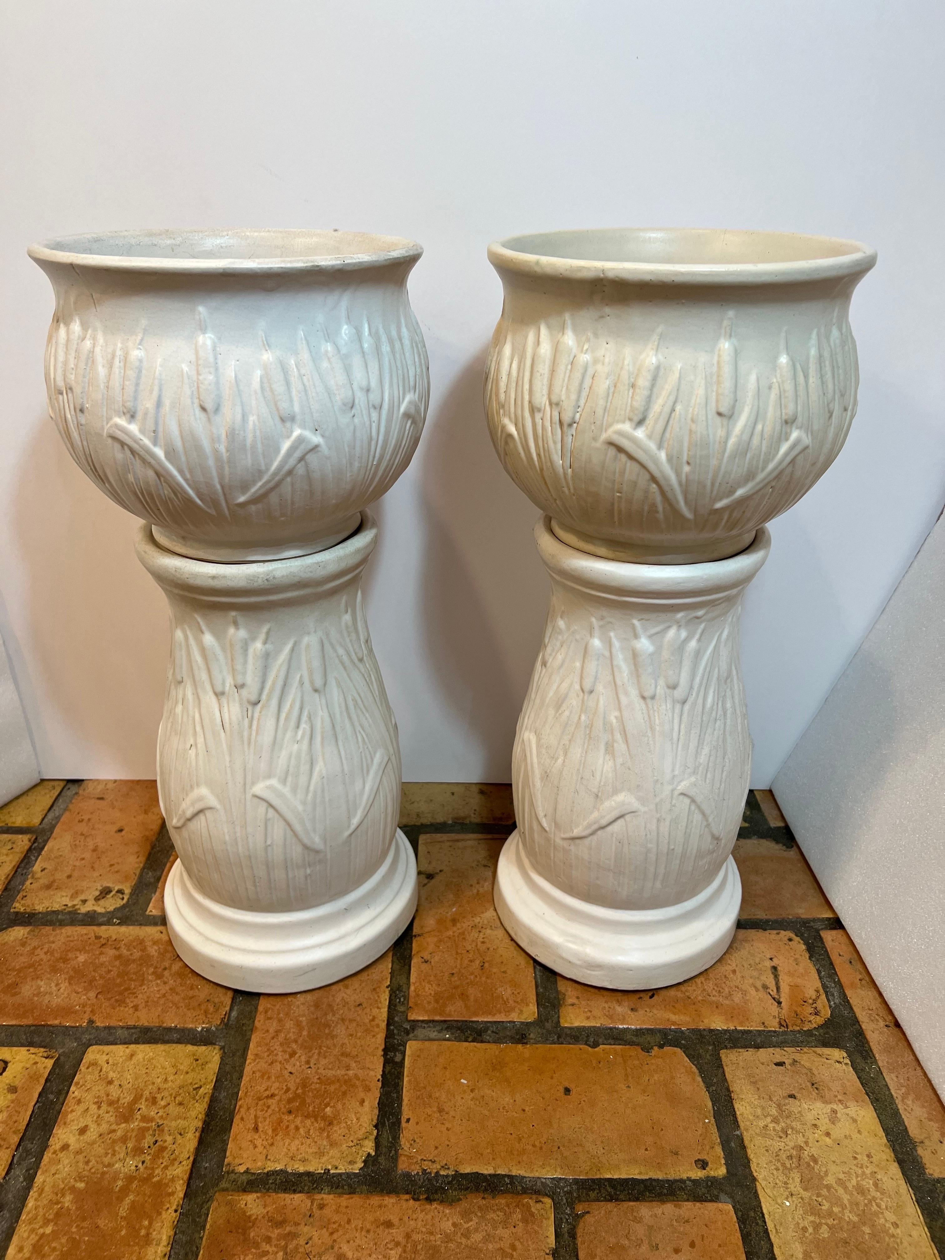 Pair of Robinson Rainsbottom Pottery Jardiniere and Pedestals with a Cattail design. Nice rare pair of matte white Cattail jardinieres and pedestals. Great set for that collector. Amazing detail to this pairs. Intricate molded exterior of Cattails