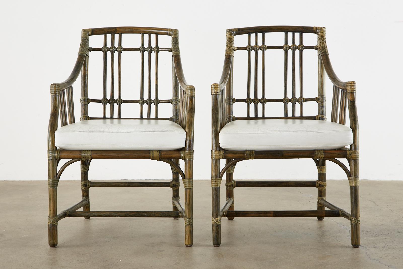 Bespoke pair of McGuire balboa armchairs featuring a custom subtle moss green finish. Beautifully crafted bamboo rattan poles with gracefully curved arms and supports. The backs have a decorative open fretwork grid pattern and the generous seat is
