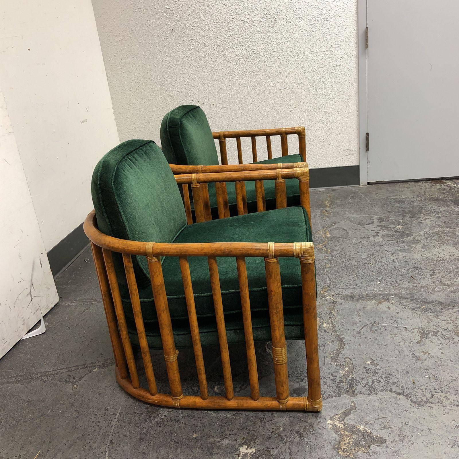 A pair of bamboo barrel chairs by McGuire. The frame consist of vertical parallel bamboo with distressed ivory leather wrap. Has removable seating and the backrest pillows upholstered in a forest green fabric. Fabric has minor aging. Measures: Arm