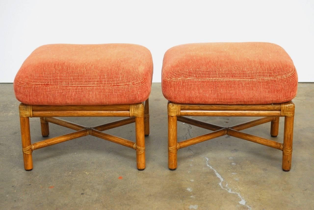 Classic pair of McGuire bamboo rattan upholstered ottomans. Featuring thick padded cushions and McGuire's leather rawhide strapping, maker's mark on bottom.