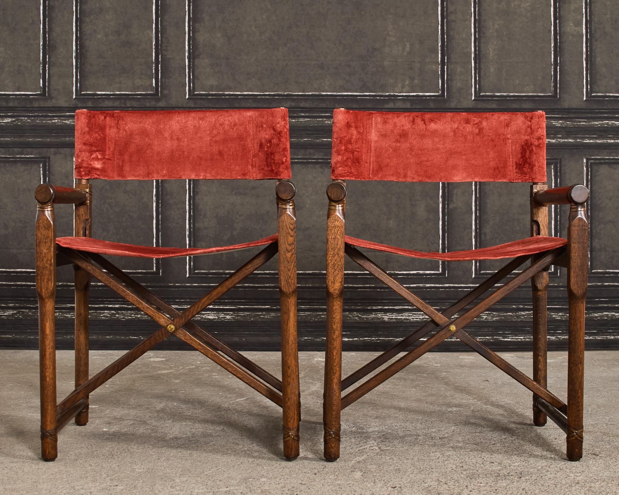Rare pair of campaign style folding directors chairs made by McGuire. The chairs feature an oak frame instead of the more common rattan pole construction McGuire is known for. The oak frames are fitted with festive paprika color velvet slings. The