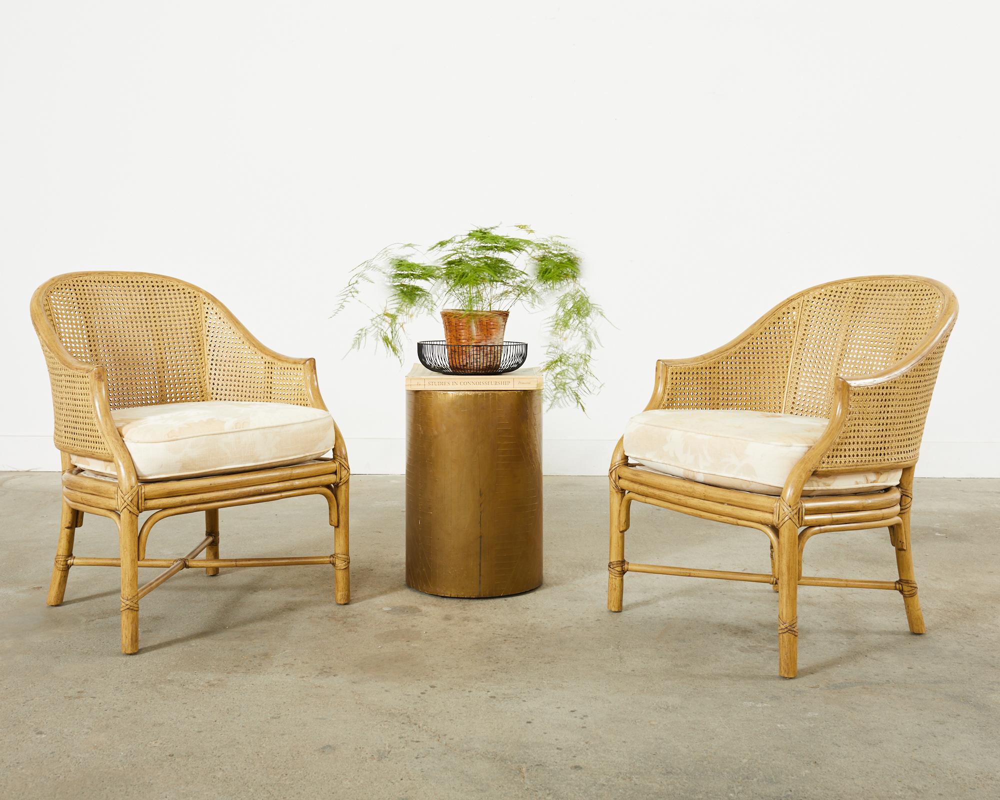 Classic pair of McGuire toboggan dining armchairs featuring a barrel-back shape. Constructed from rattan frames with double-wall caned sides. The seat has a thick fitted loose seat cushion in a linen fabric with a subtle foliate motif. The rattan is