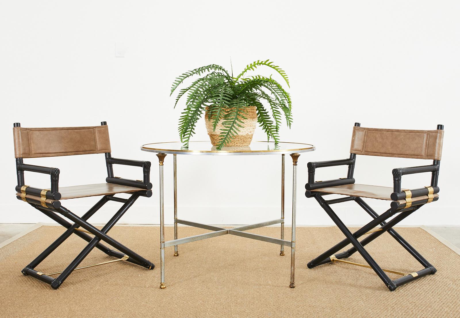 Dramatic pair of directors chairs or dining armchairs made by McGuire. The pair feature oak frames with a lacquered, ebonized finish having leather rawhide laces on the exposed joints. The folding chairs are made in the campaign style with brilliant