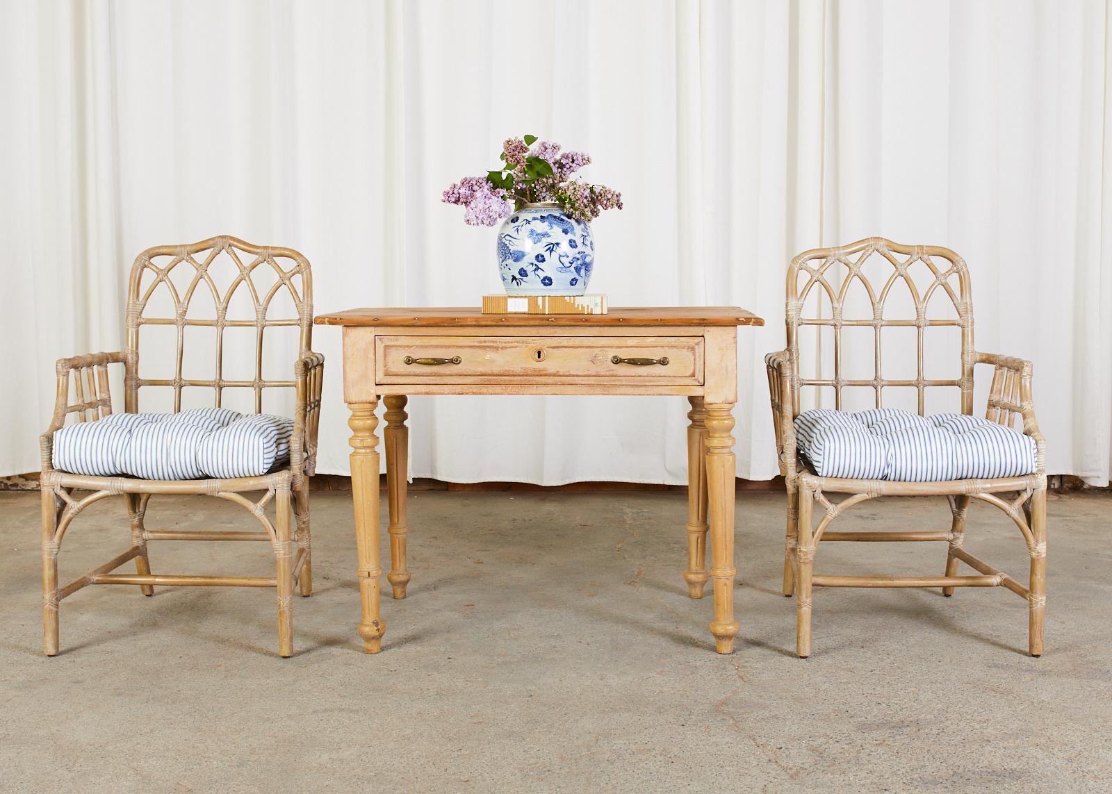 Distinctive genuine pair of McGuire bamboo rattan dining armchairs featuring a cerused lacquer finish. The chairs are crafted from rattan poles with a gothic lancet arch design on the backs and an open fretwork on the sides in a Chinese Chippendale