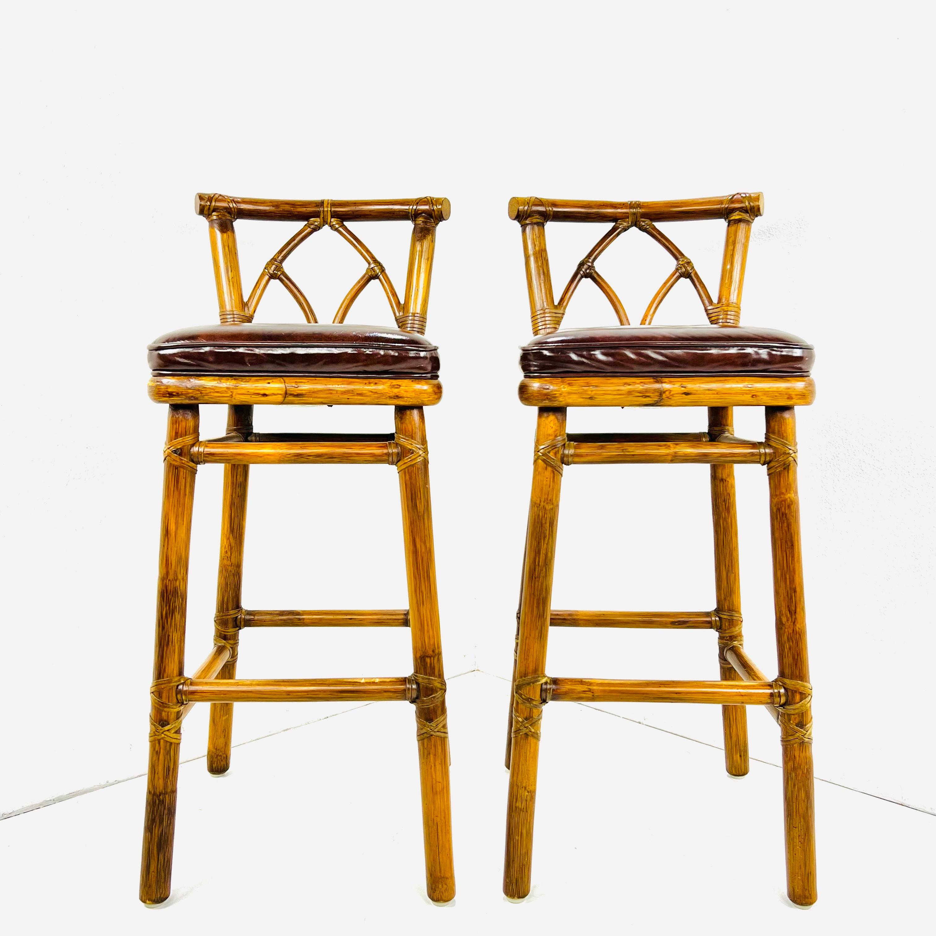 Genuine pair of rattan bar stools made in the California organic modern style by McGuire, San Francisco. The chairs feature a thick rattan pole frame lashed together with leather rawhide laces. Decorated with an arch motif back splat and topped with