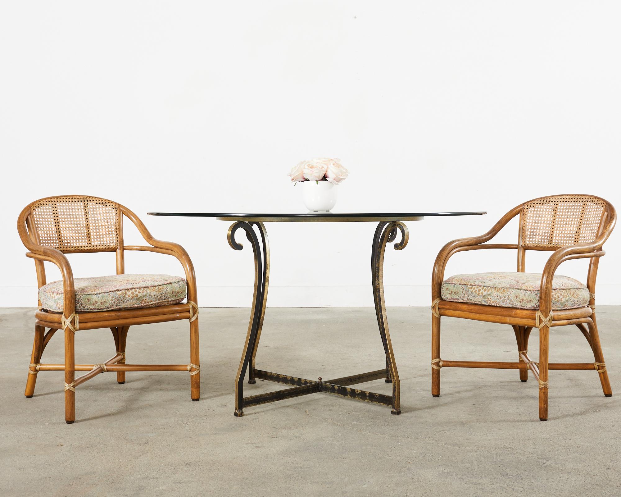 Graceful pair of bent rattan armchairs or dining chairs made in the California coastal organic modern style by McGuire. The chairs feature a thick pole rattan frame inset with woven honeycomb cane on the seat backs. Each seat has a thick fitted seat