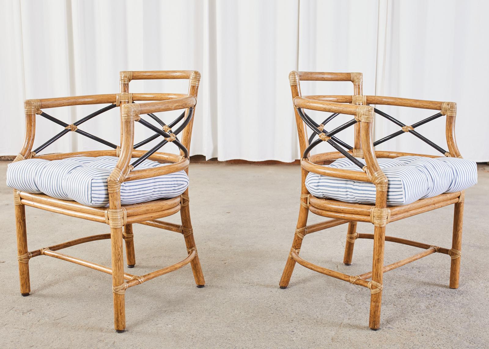 Stylish pair of rattan barrel back dining armchairs designed by Elinor McGuire in the California organic modern style. The armchairs feature a curved bentwood rattan frame with an X form motif having an ebonized finish. The seat measures 16 inches