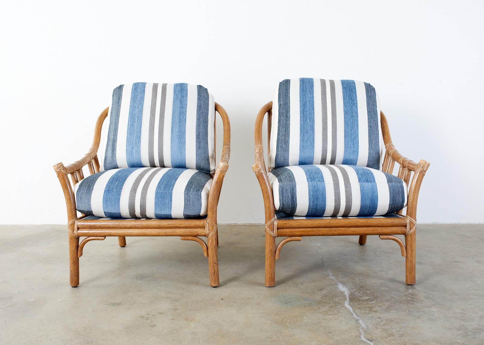 Gorgeous pair of McGuire oversized bamboo rattan lounge chairs made in the California organic modern style. The chairs feature a large bent rattan frame fitted with thick linen and chenille striped cushions. The frames are lashed together with