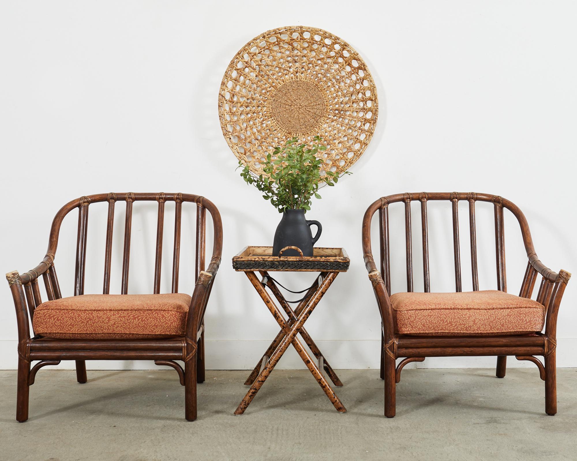 Distinctive pair of rattan lounge chairs or armchairs made in the California coastal organic modern style by McGuire. Large chairs featuring a bent pole rattan frame lashed together with leather rawhide laces and caps. The generous seats have fitted