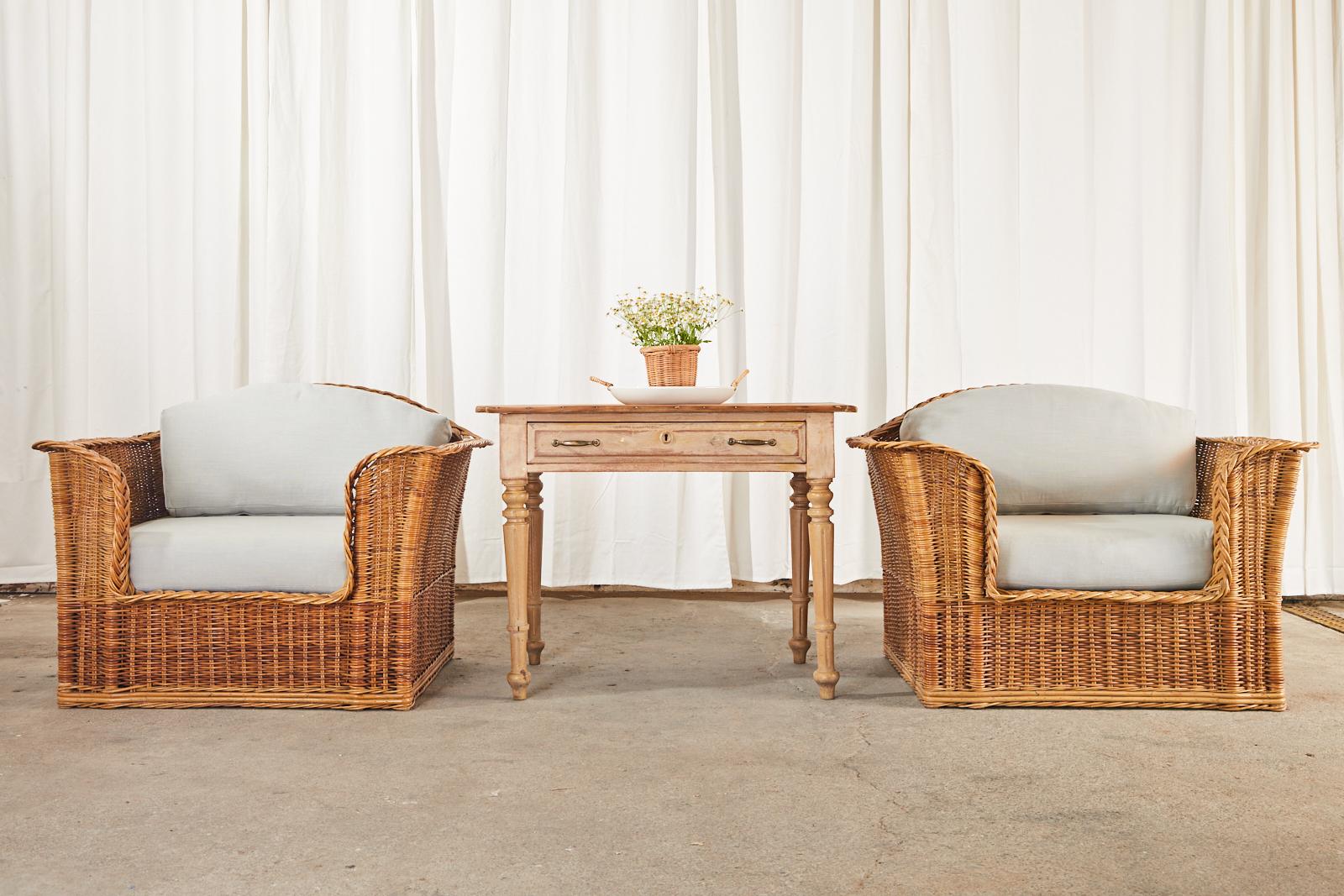 California organic modern style pair of rattan and stick wicker lounge chairs by McGuire. Constructed with rattan frames covered with woven wicker having braided arms and trim. Excellent joinery and craftsmanship with a flared cube profile. These