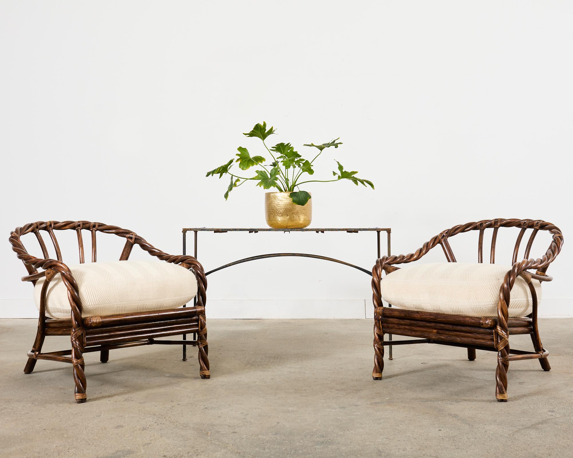 Fabulous and rare pair of rattan lounge chairs or club chairs crafted by McGuire in the California organic modern style. These iconic chairs feature bent rattan poles twisted together resembling rope. Gracefully curving back and arms support thick