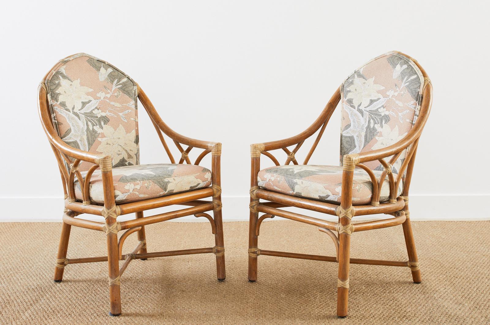 Gorgeous pair of genuine McGuire rattan dining armchairs featuring a lovely floral print fabric upholstery. Made in the California organic modern style constructed from rattan poles lashed together with leather rawhide laces. The backs and sides