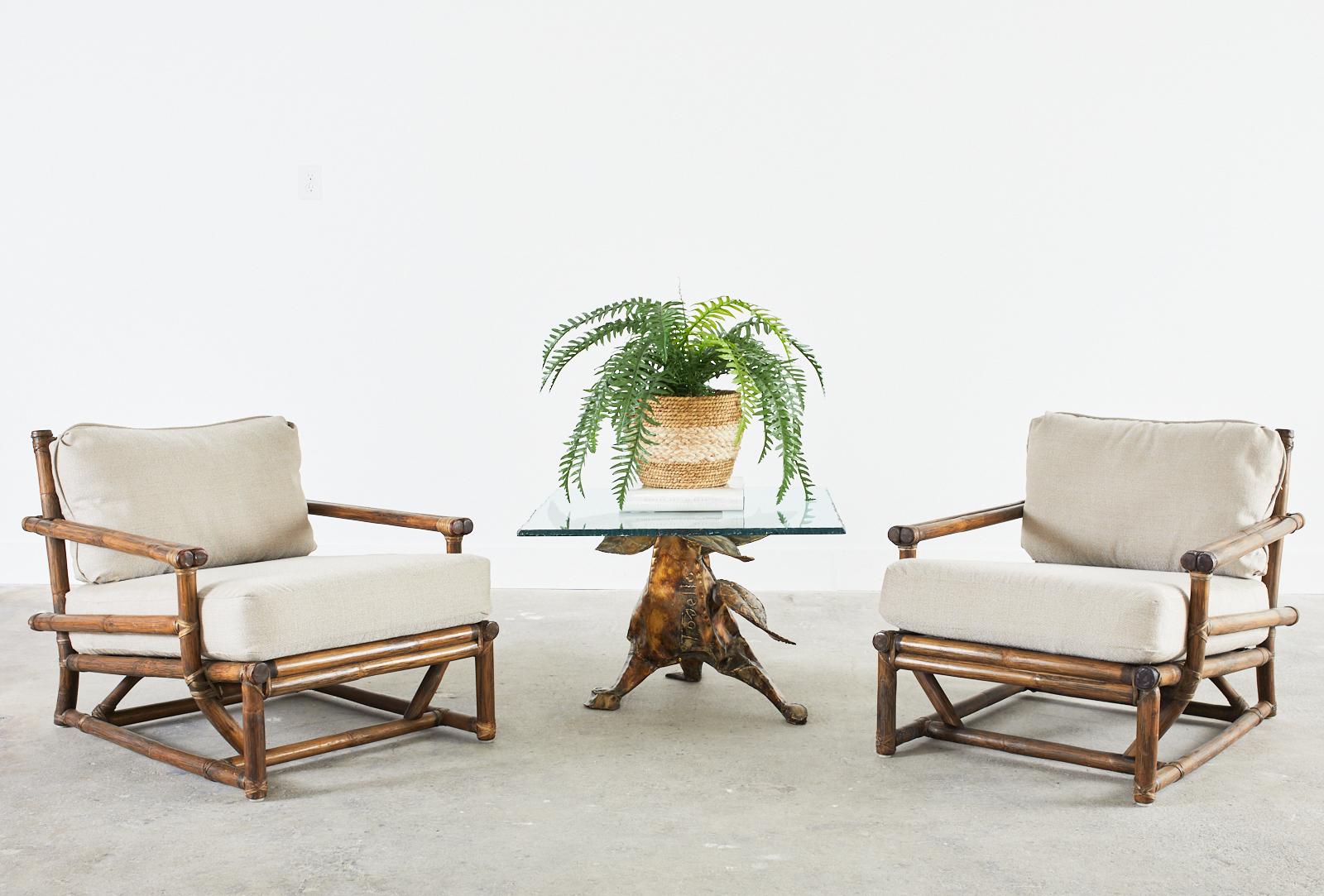 Stylish pair of rare McGuire lounge chairs with a low profile in the Asian style. Late 20th century creations made in the California organic modern style by McGuire. The chairs feature thick rattan poles lashed together with leather rawhide laces