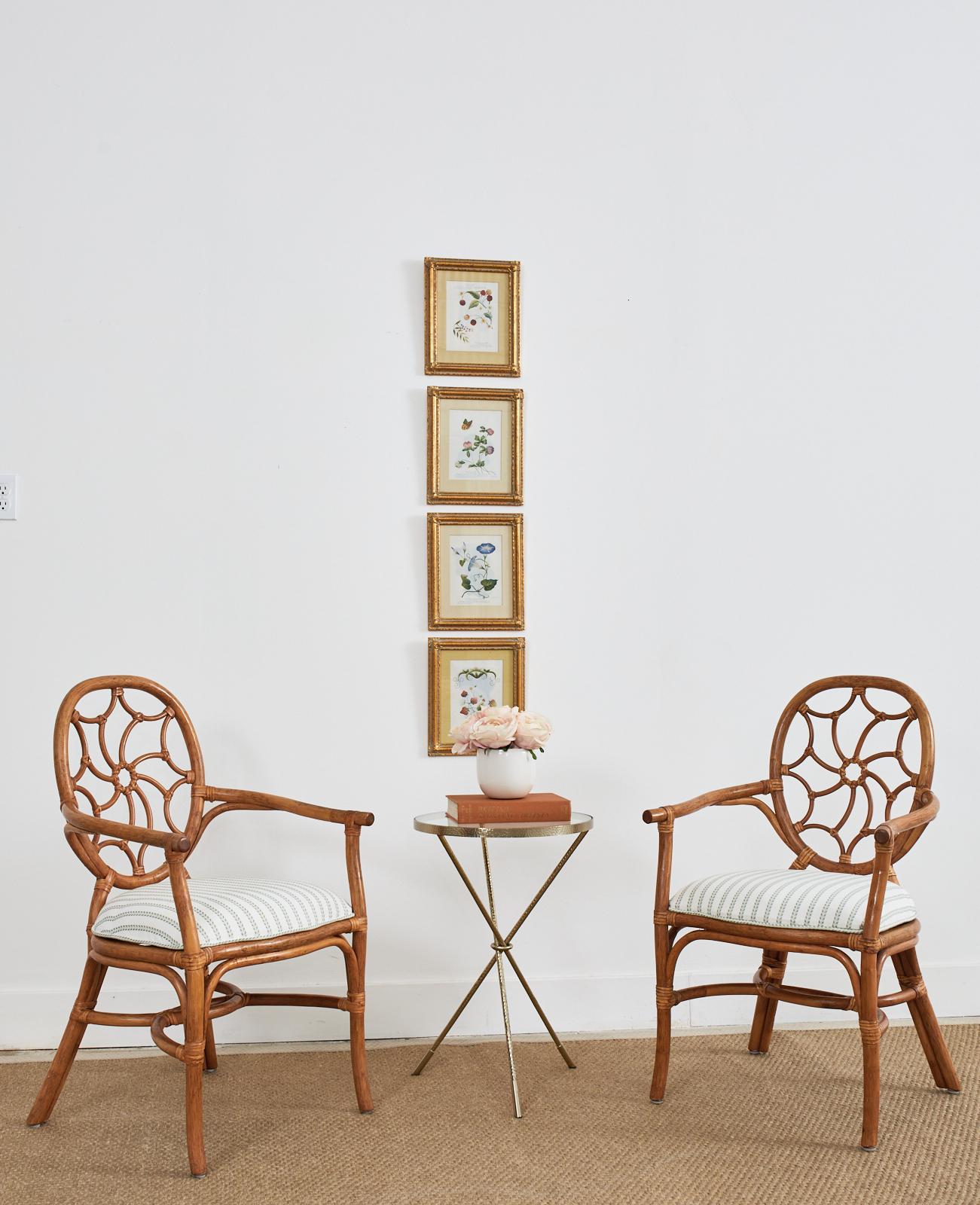 Distinctive pair of organic modern rattan dining armchairs crafted from rattan in the style and manner of McGuire. The chairs feature a round back with a wheel motif back splat. The rattan is lashed together with leather rawhide laces a la McGuire.