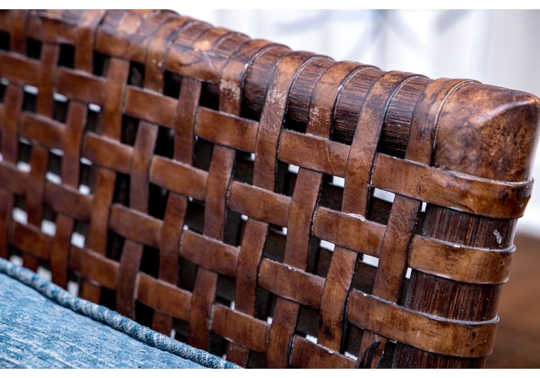 Part of the Antalya Collection by McGuire Furniture with rattan construction and laced with durable woven faux eather strapping. The chair with gently flared armrests, generous loose cushion seat and back, barrel back and resting on round feet. The