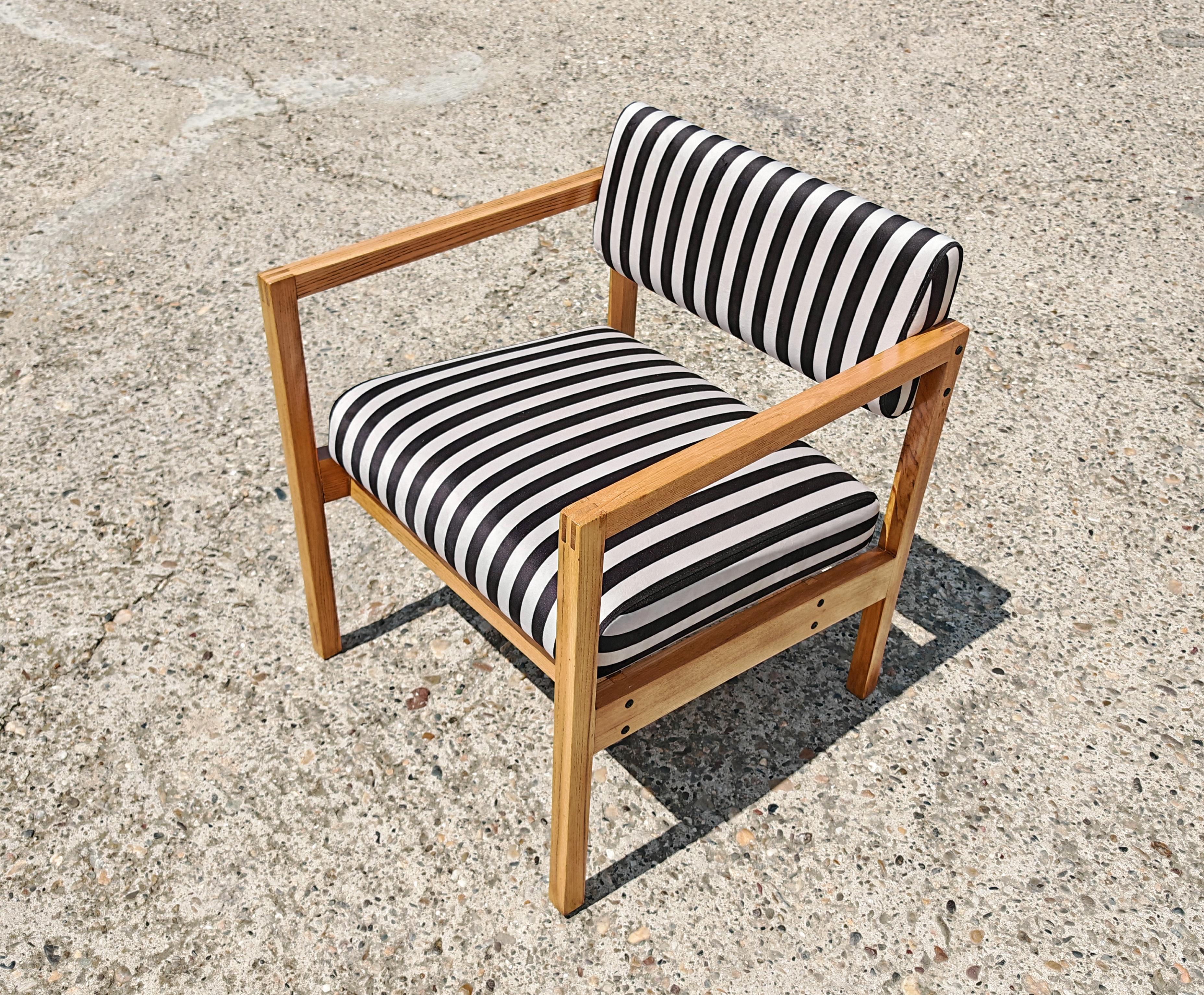 In this listing you will find a pair of stunning and very sleek Mid Century Modern Armchairs made of solid Ash. They feature geometric shape with clean lines, enhanced with a selection of black and white plush with stripes. This combination of warm