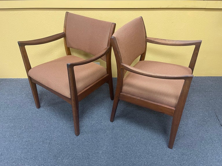 Pair of MCM walnut framed arm chairs in the style of Jens Risom for Johnson Furniture Co., circa 1960s. The chairs are in good vintage condition with original upholstery and measure as follows: Armchair: 24.75