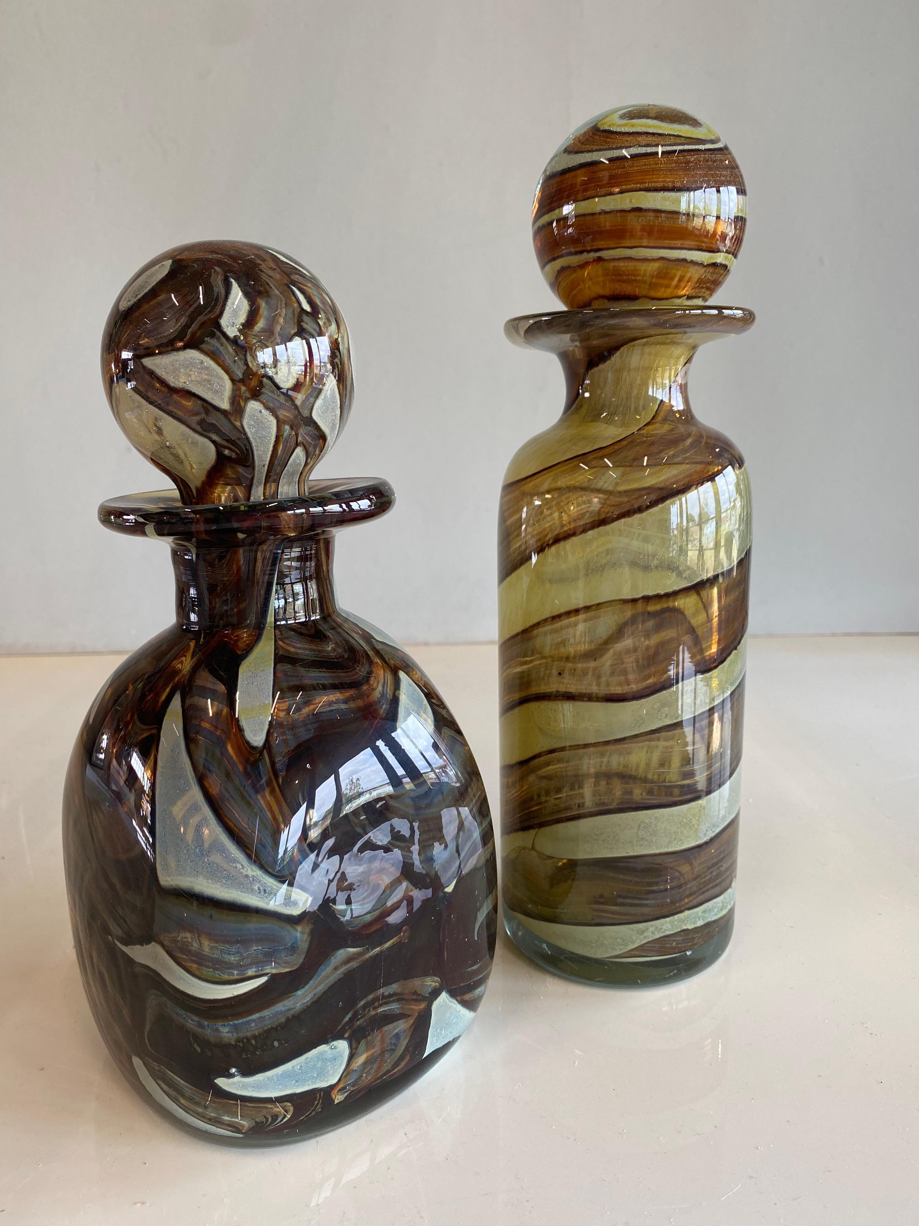 This pair of heavy and finely crafted decanters are from the Mdina Glass company and date from around the 1970s. The two carafes have a balloon-shaped stopper, which can certainly be seen as a recognition feature for the Mdina company.
They are