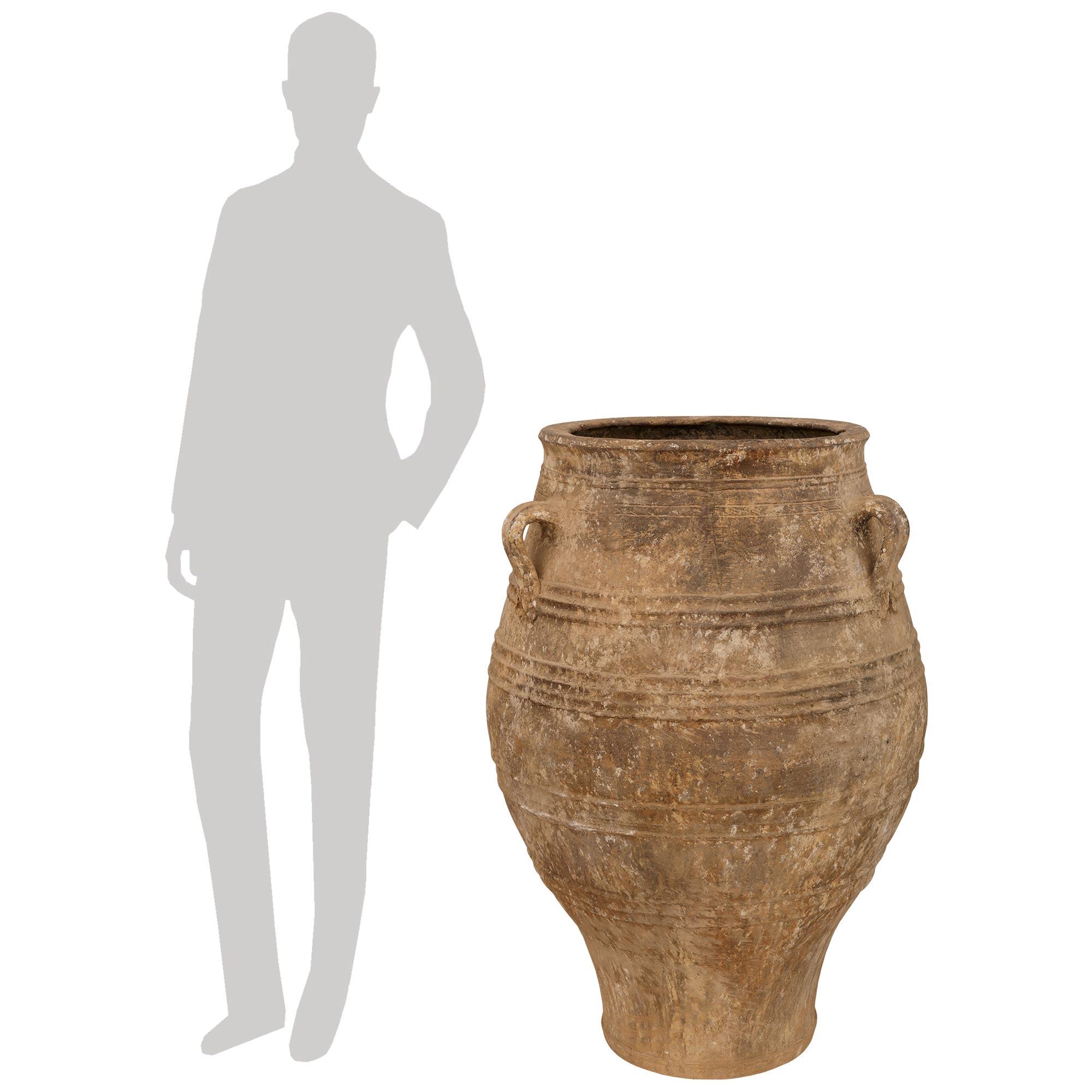 A stunning and large scale pair of Mediterranean 19th century patinated Terra Cotta olive jars. Each beautiful and extremely decorative olive jar displays a most elegant curved baluster like shape with three scrolled handles above and all their