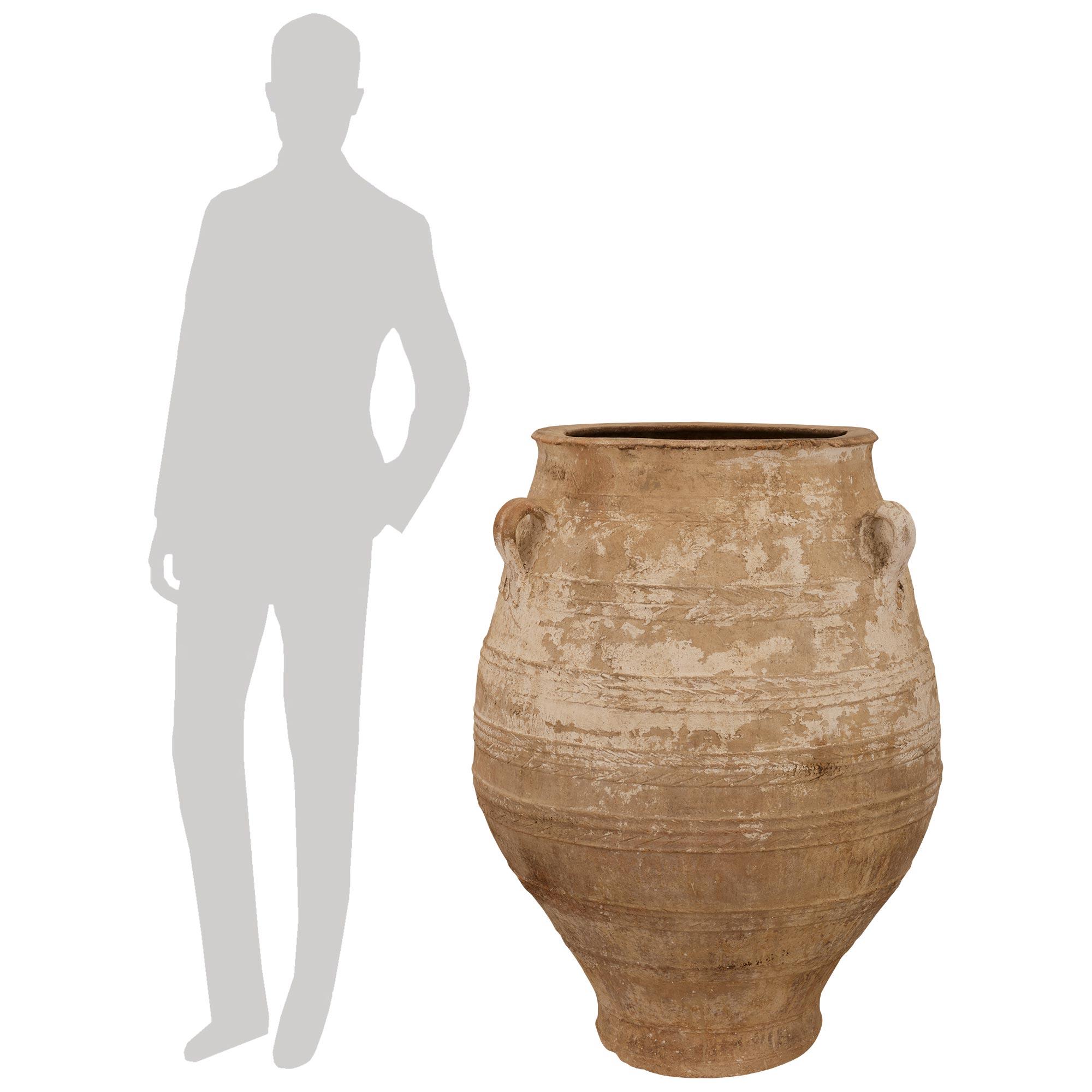 A handsome and large scale pair of Mediterranean 19th century patinated Terra Cotta olive jars. Each beautiful and extremely decorative olive jar displays a most elegant curved baluster like shape with three scrolled handles above and all their