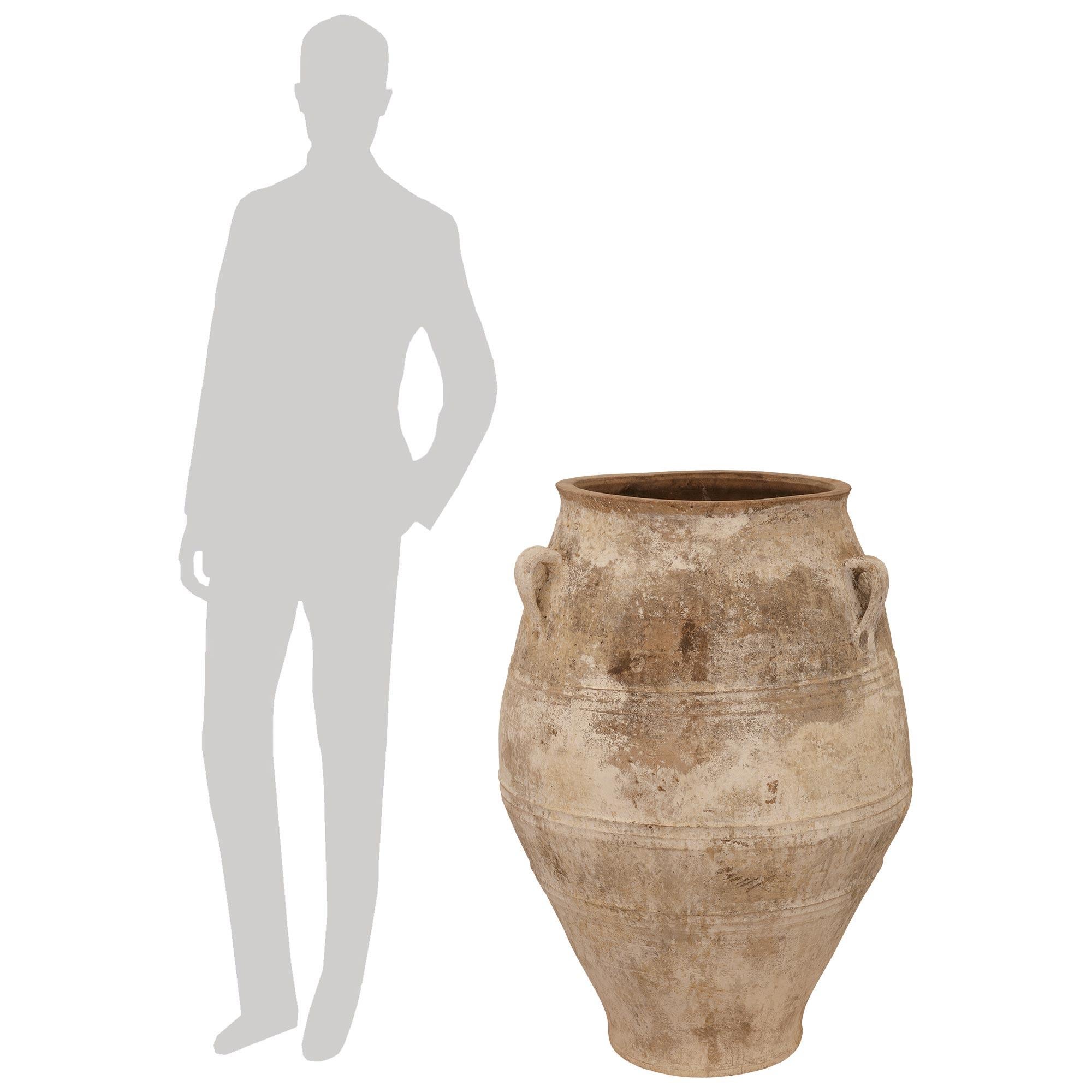 Magnifique paire de jarres à olives en terre cuite patinée du XIXe siècle. Chaque jarre à olives, magnifique et extrêmement décorative, présente une forme de balustre incurvée des plus élégantes, avec trois anses en volute au-dessus et une patine