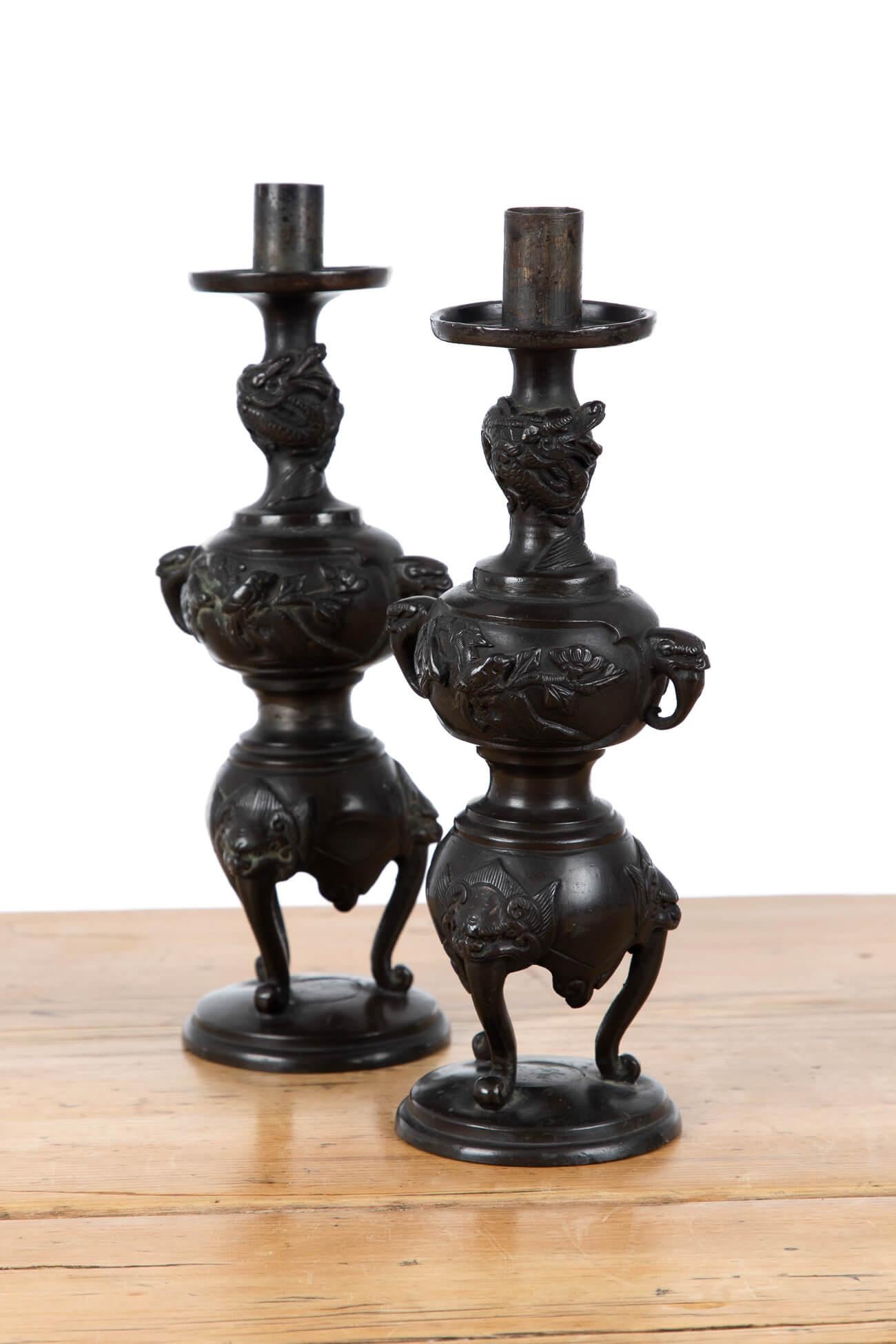 A pair of decorative Meiji Period Japanese bronze candlesticks. Adorned with birds and elephant trunk handles, raised on three lion-mask cabriole legs. Acquired from the collection of the late Alfred Theodore Arber-Cooke who was a passionate