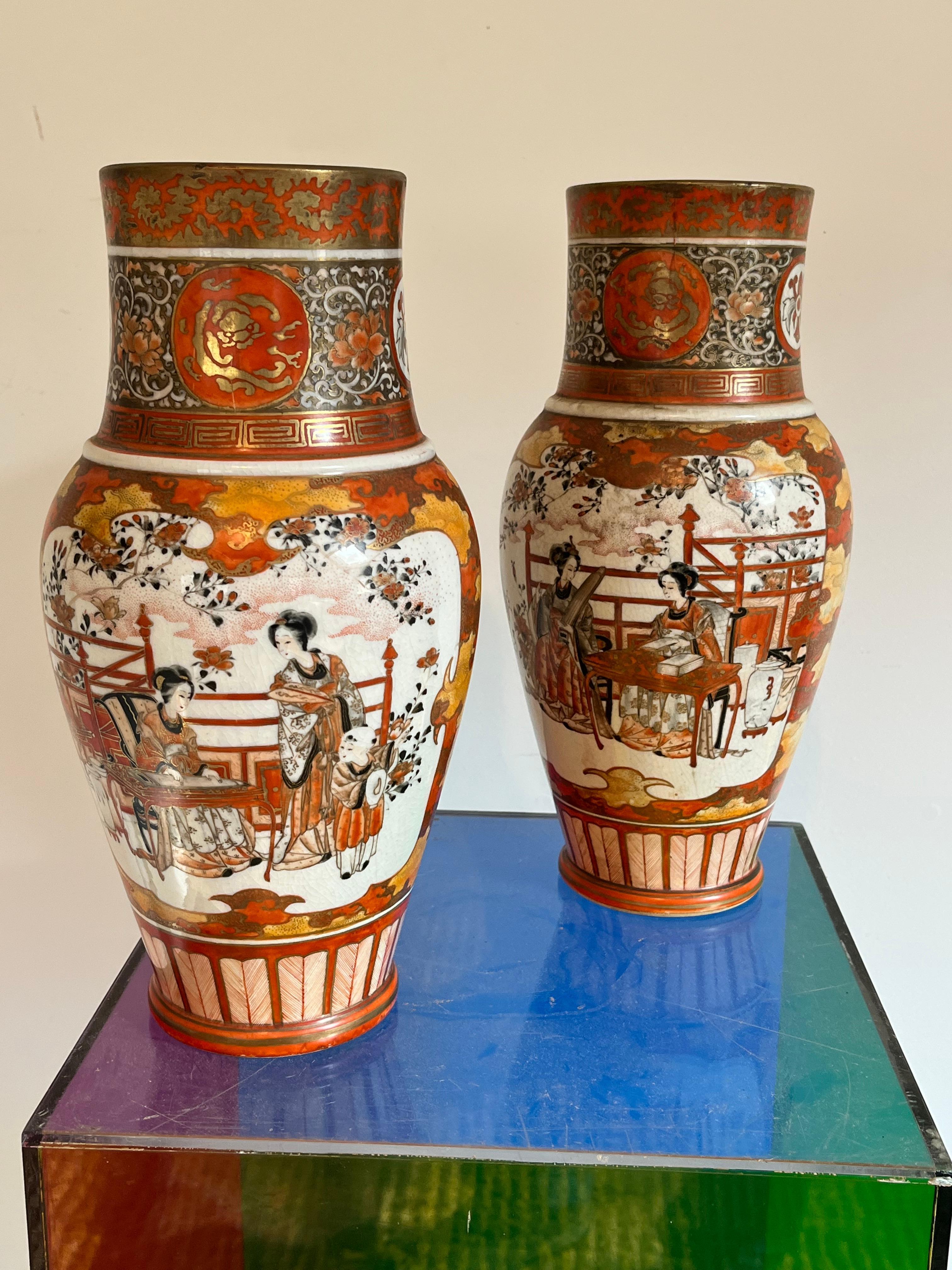A fine pair of Japanese porcelain vases in the Kutani manner, hand-painted with figural panels depicting women engaged in various occupations, the reverse with floral and bird decoration, red/orange borders with parcel gilt details, the bases each