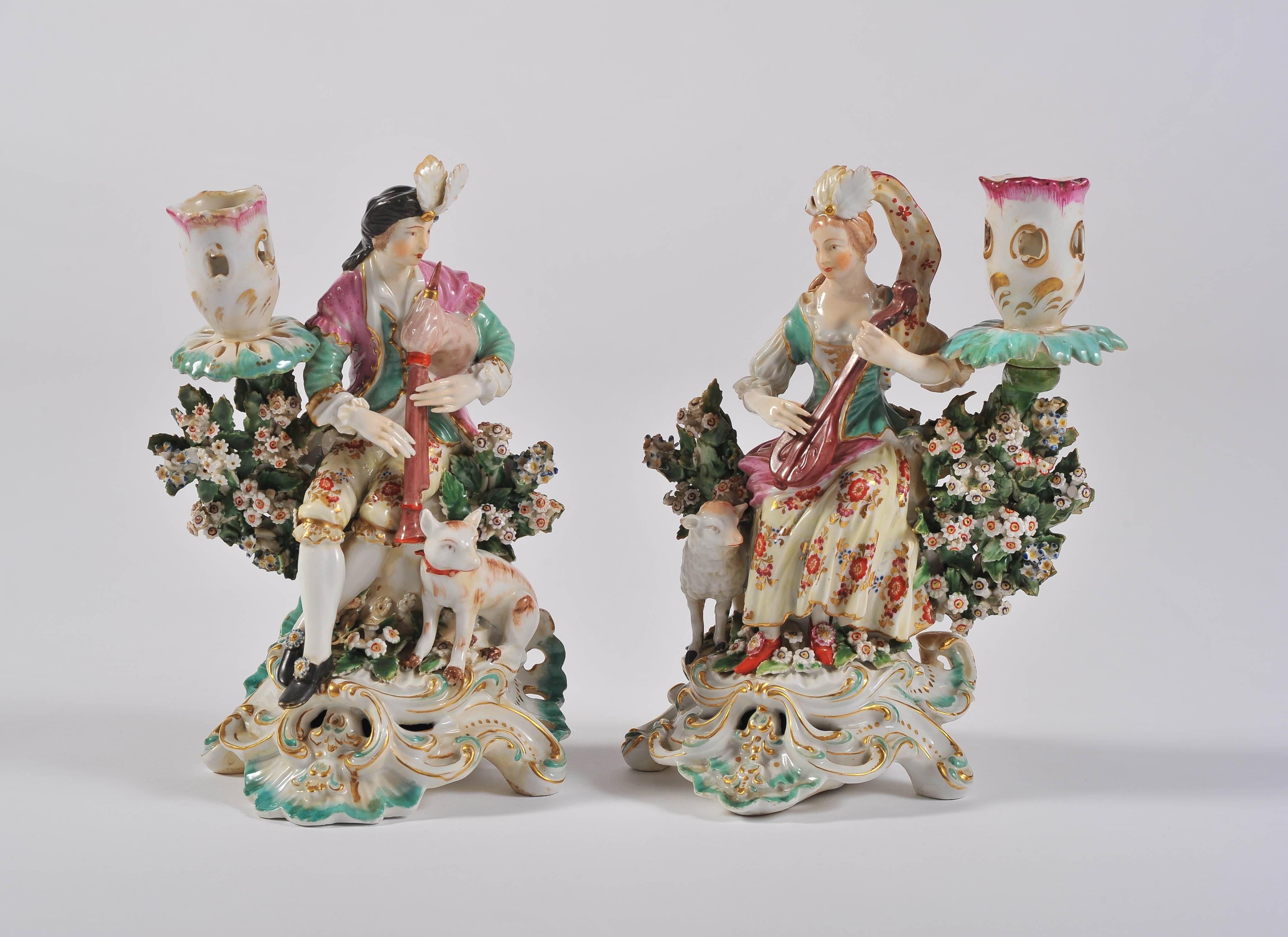 This delightful hand-painted pair of porcelain figurines depict a boy and a girl playing musical instruments, him with a dog, her with a lamb and each with a candle holder.
With delicate flowers on gilt and painted scroll bases.
All colors
