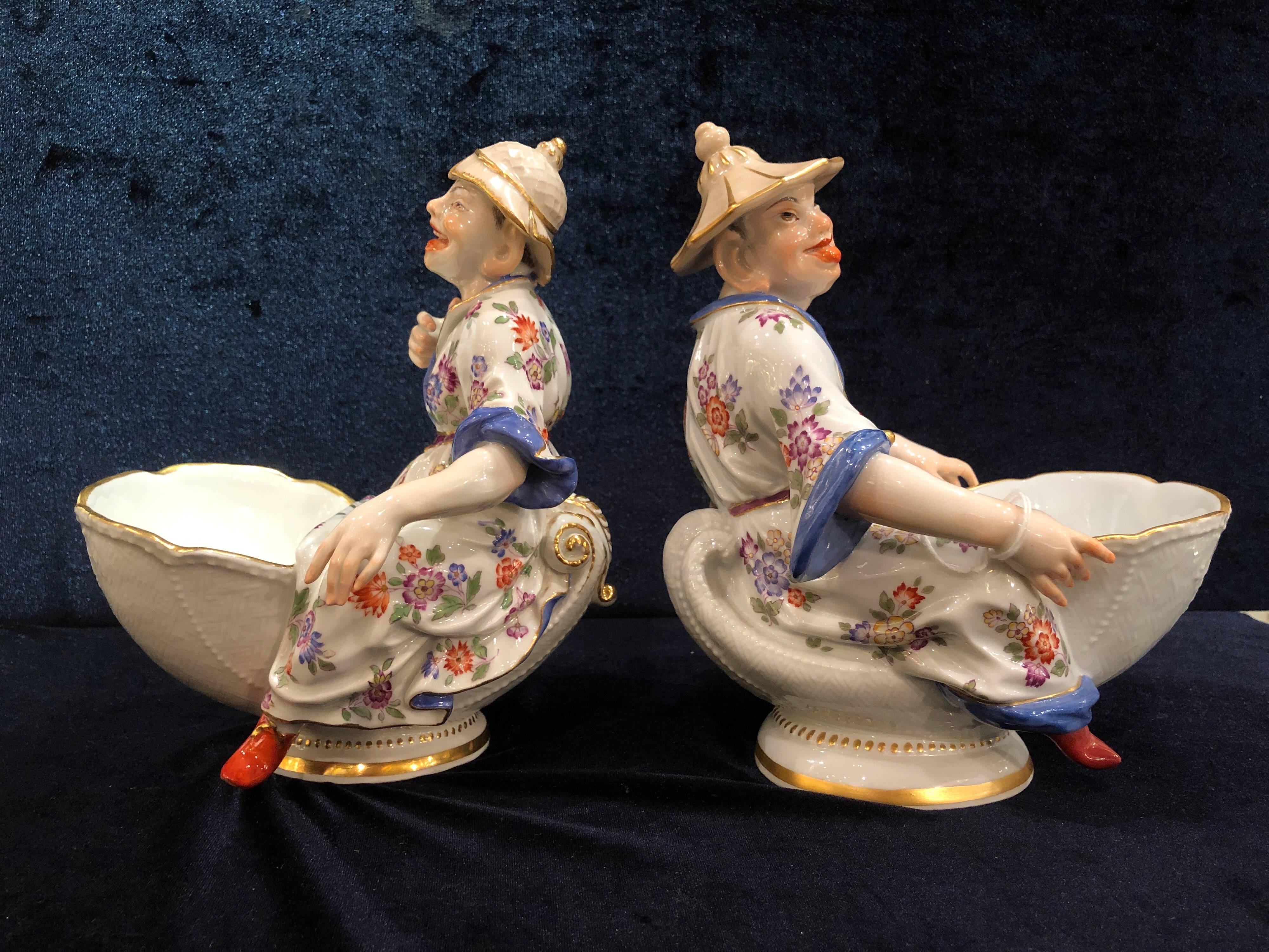 Ein feines Paar Meissener Porzellan Chinoiserie Figurensüßspeisen, nach einem Modell von J.J. Kandler
Jeweils mit einer auf einer Muschel sitzenden Malabar-Chinoiserie-Figur, die eine Schale vor sich hält, Korbgeflecht-Ritzdekor auf den Muscheln,