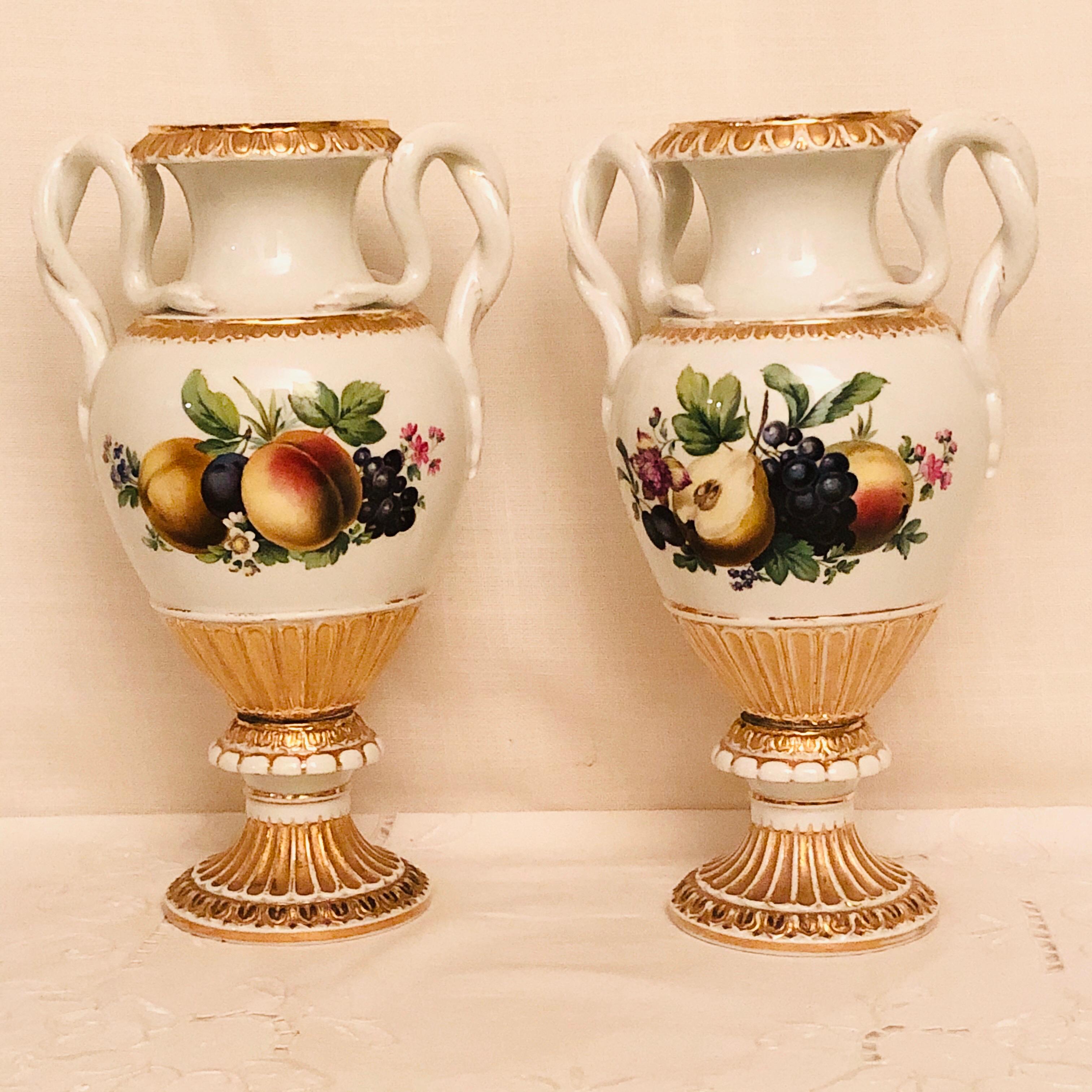 Pair of Meissen vases with snake handles and different still life paintings of fruit on all four sides. The paintings of fruit on these vases are so well done that the fruits look real. They would be a fabulous decoration on your mantel (fireplace),